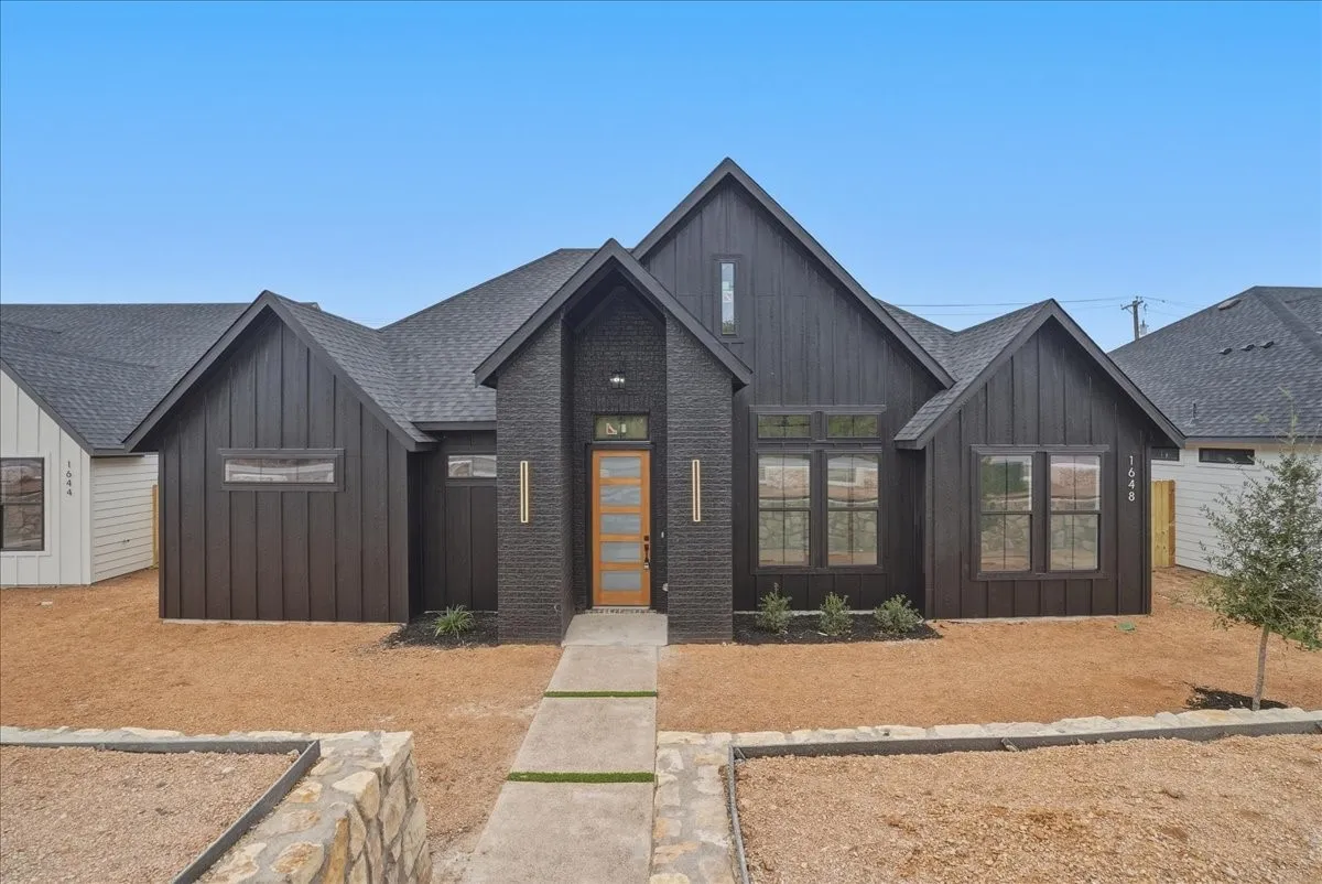 Modern facade with dark vertical siding and dark brick accents