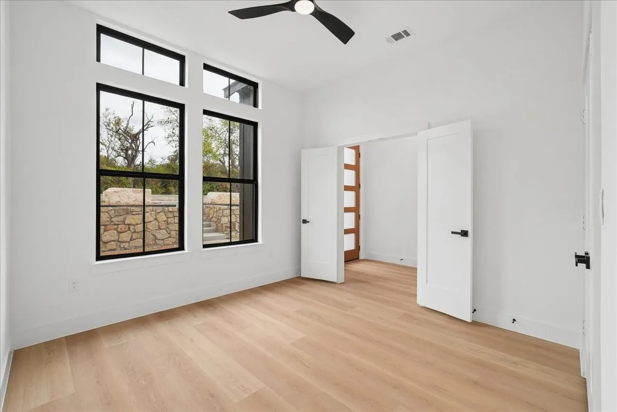 Wood-finish flooring, white walls, and a black ceiling fan