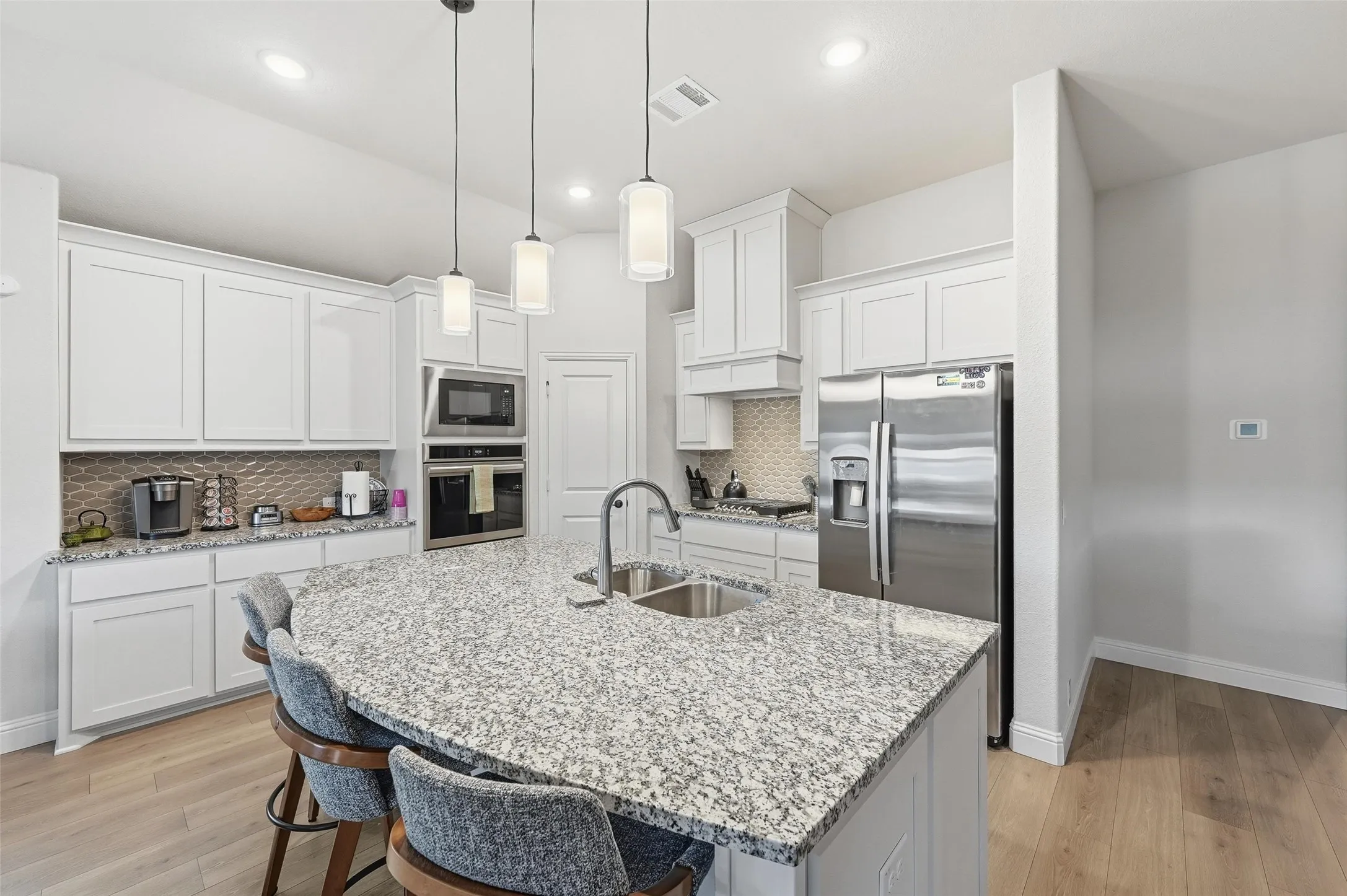 Kitchen featuring a large island with granite countertops, stainless steel appliances, white cabinetry, and recessed lighting