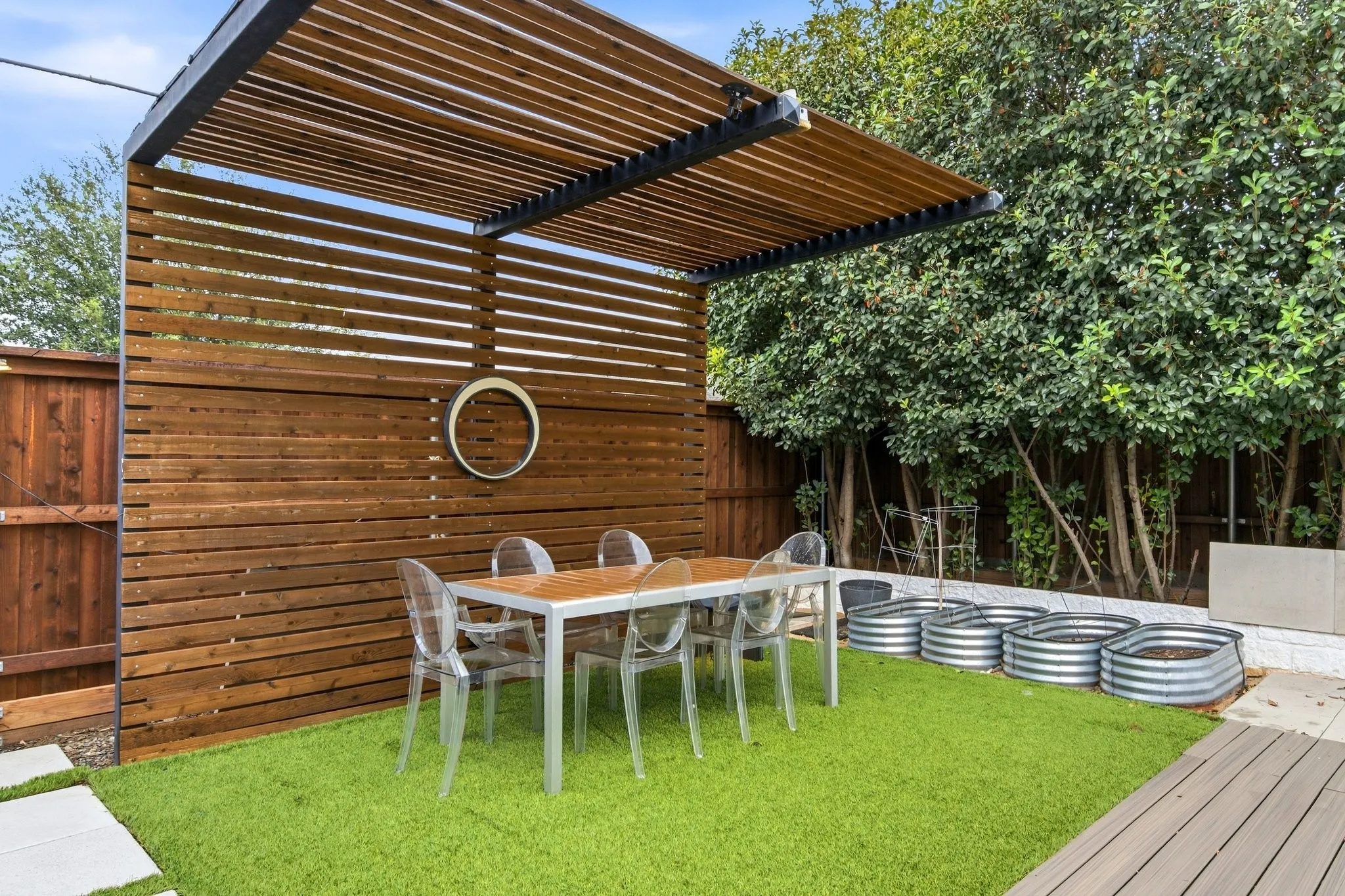Outdoor oasis with low-maintenance turf, shaded pergola, and lush perimeter privacy