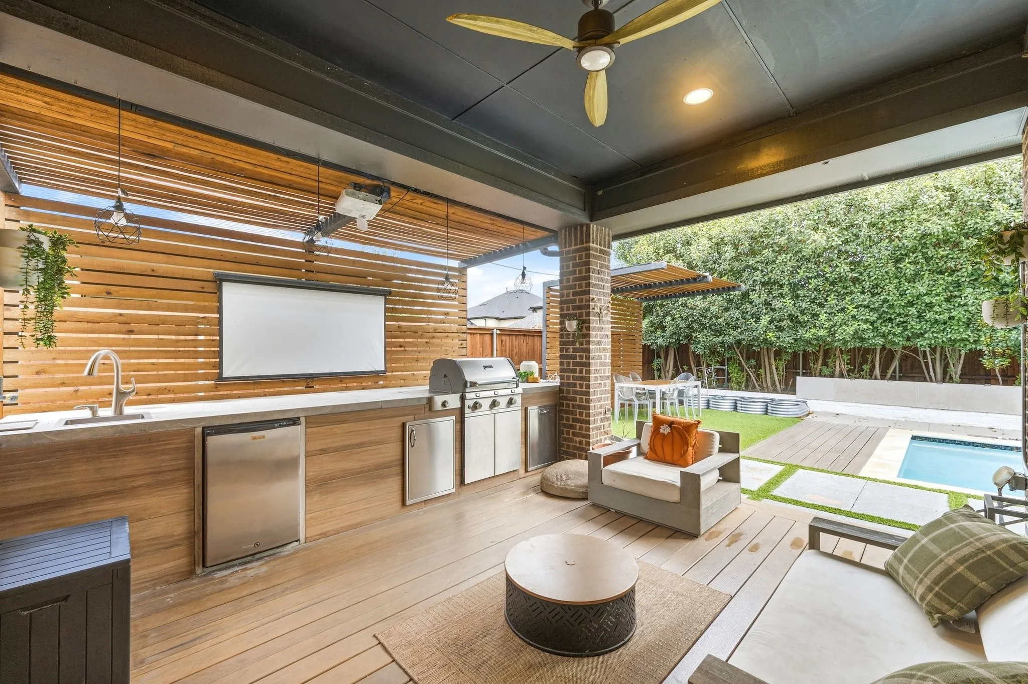 High-end outdoor living center featuring built-in fridge, sink, and outdoor projector screen.