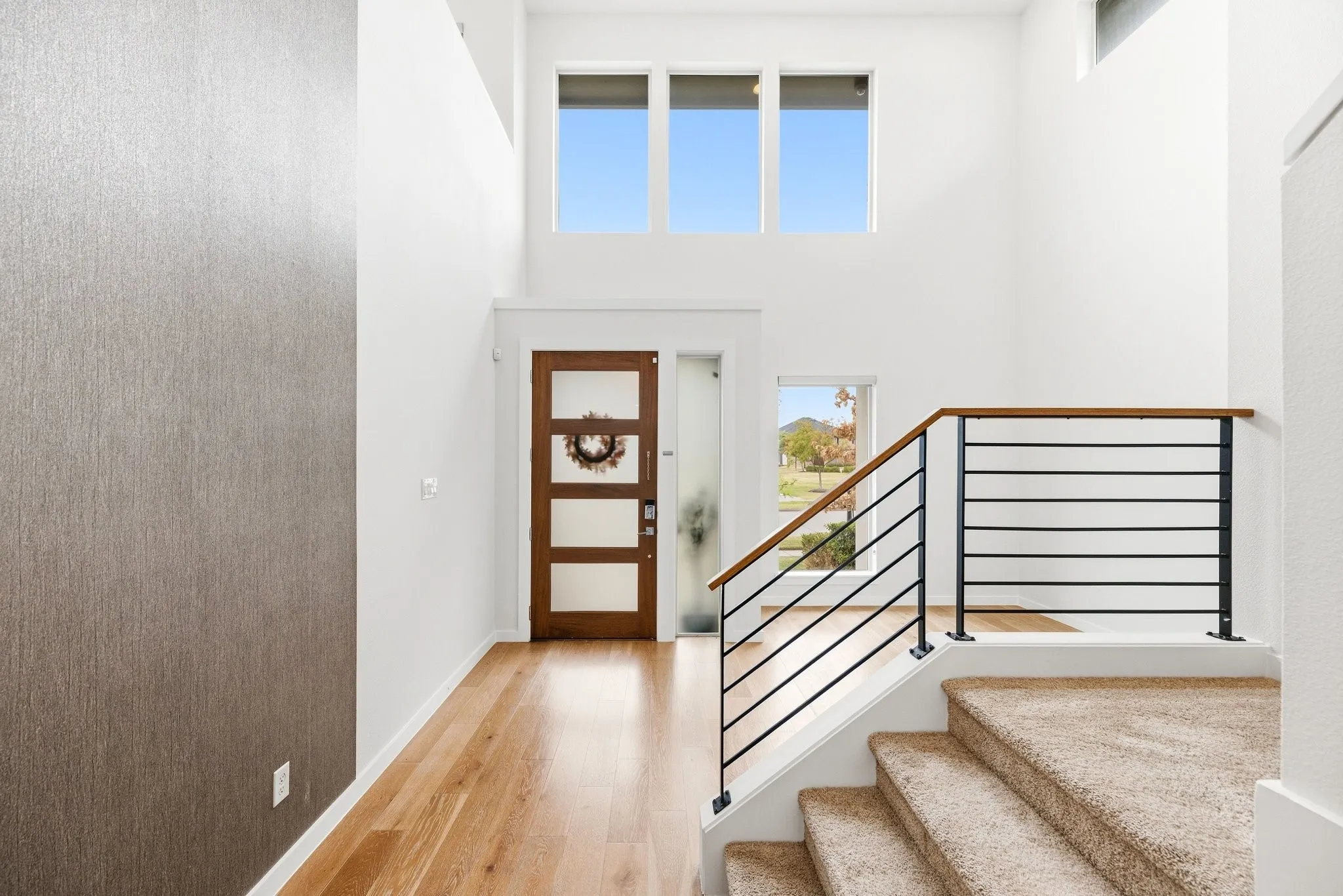 Grand entryway featuring a stylish floating staircase and abundant natural light.