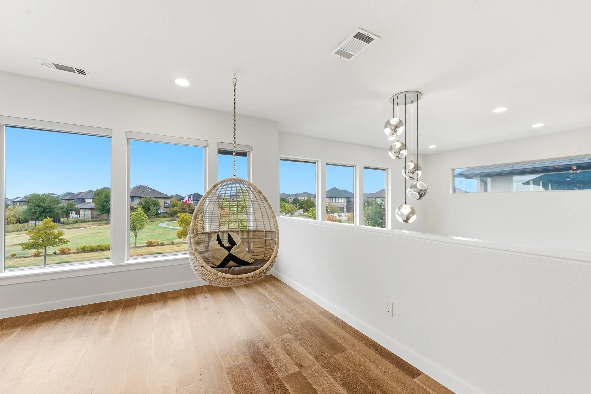Flexible second-floor living space featuring light hardwoods and statement designer lighting.