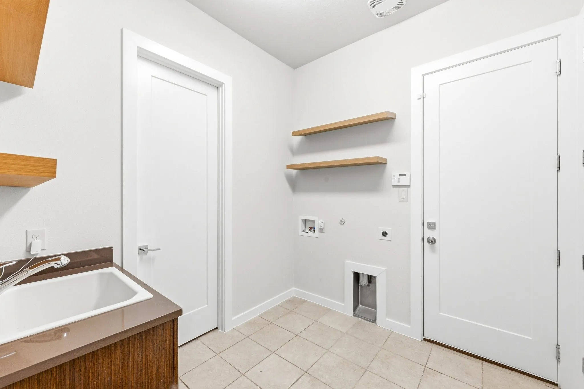 Dedicated laundry room equipped with built-in cabinetry, counter space, and utility sink.