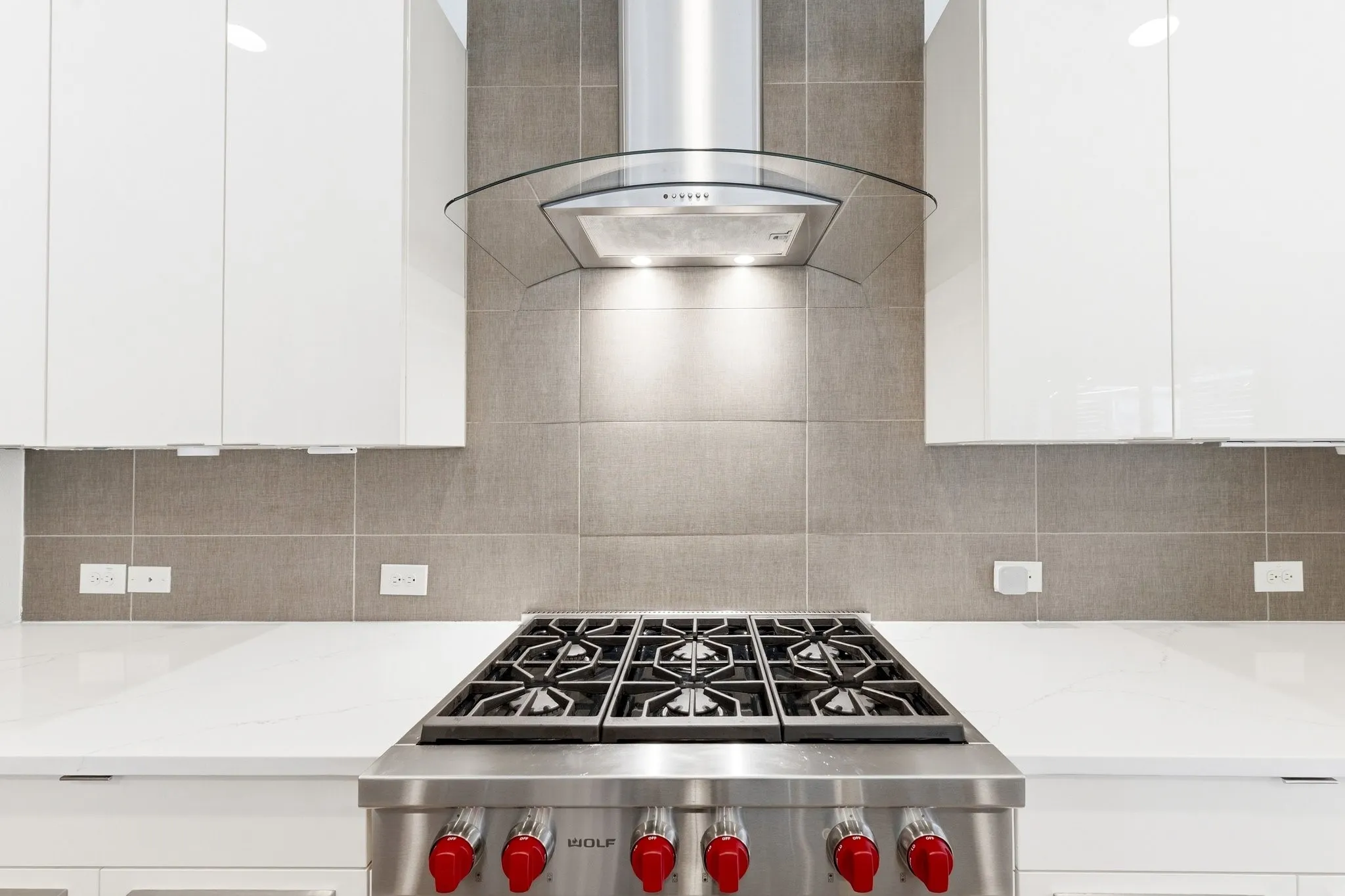 Professional Wolf gas cooking range and modern ventilation hood for culinary enthusiasts.