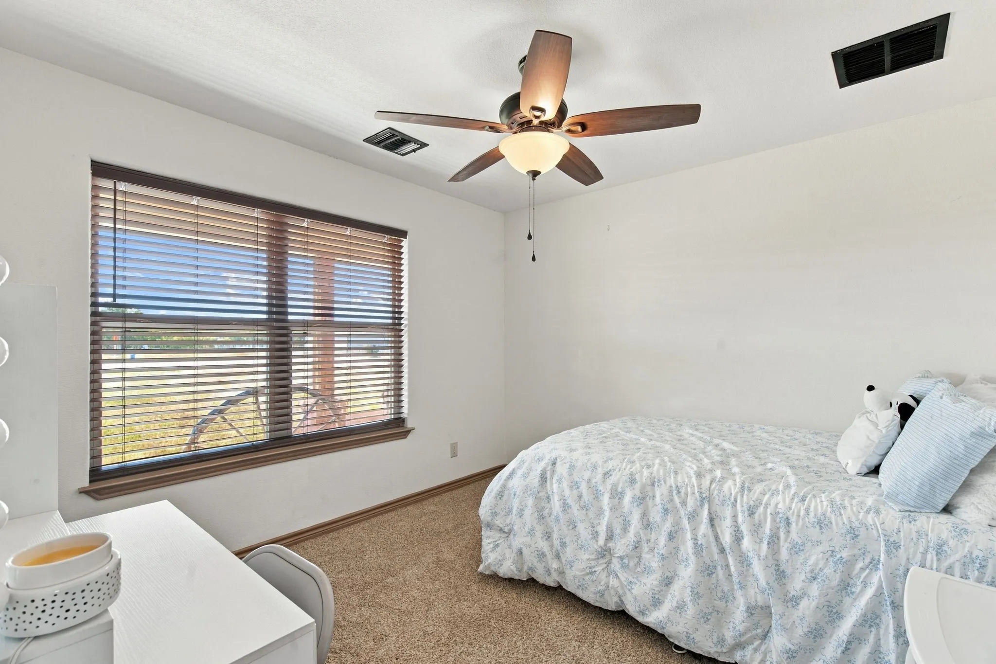 Neutral wall paint, light-toned carpeting, and a ceiling fan with integrated lighting