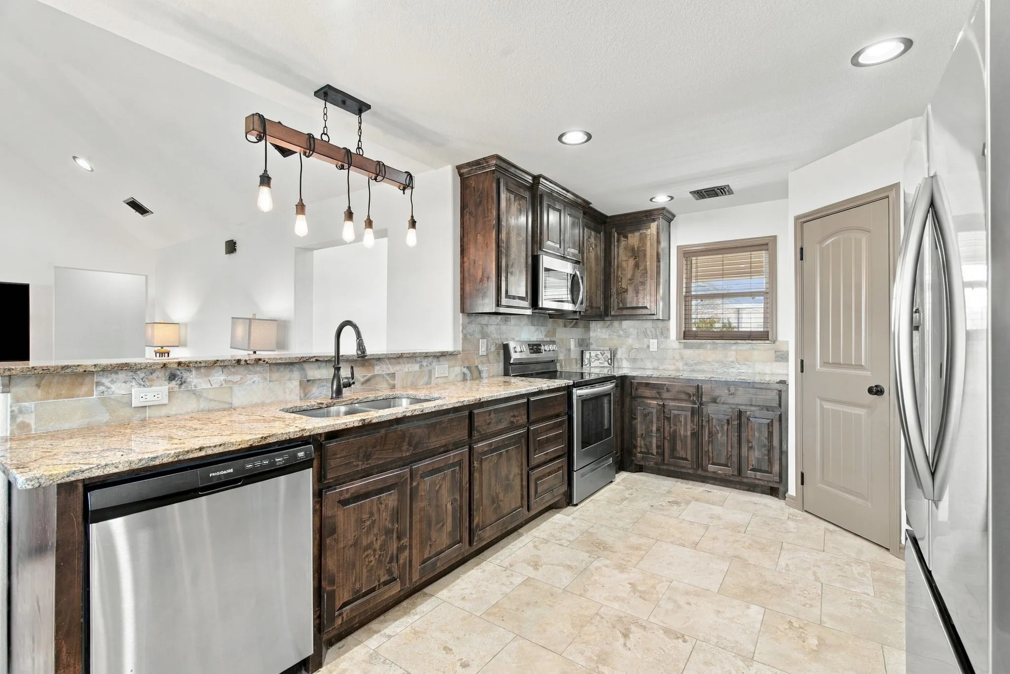 Kitchen featuring wood cabinetry, stainless steel appliances, a double basin sink, and recessed lighting
