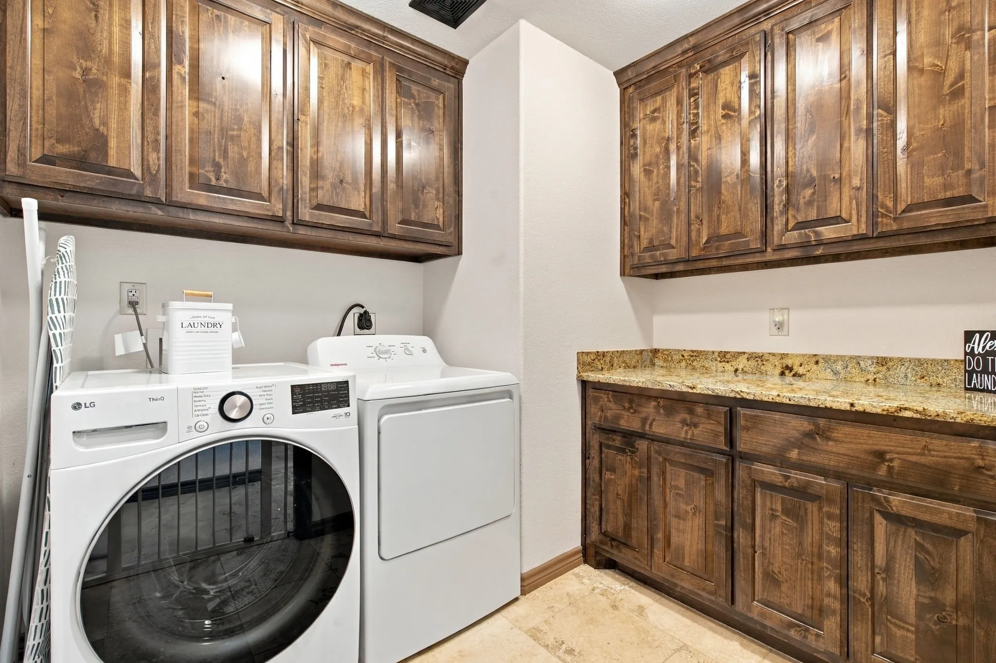 Upper and lower wood-finish cabinetry, stone countertop, and tile flooring