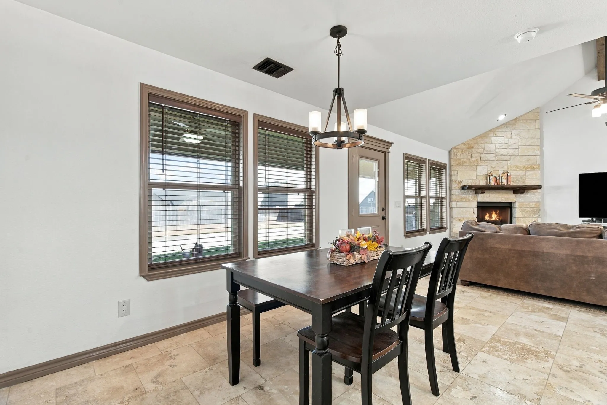Vaulted ceiling featuring a stone-clad fireplace and wood mantel