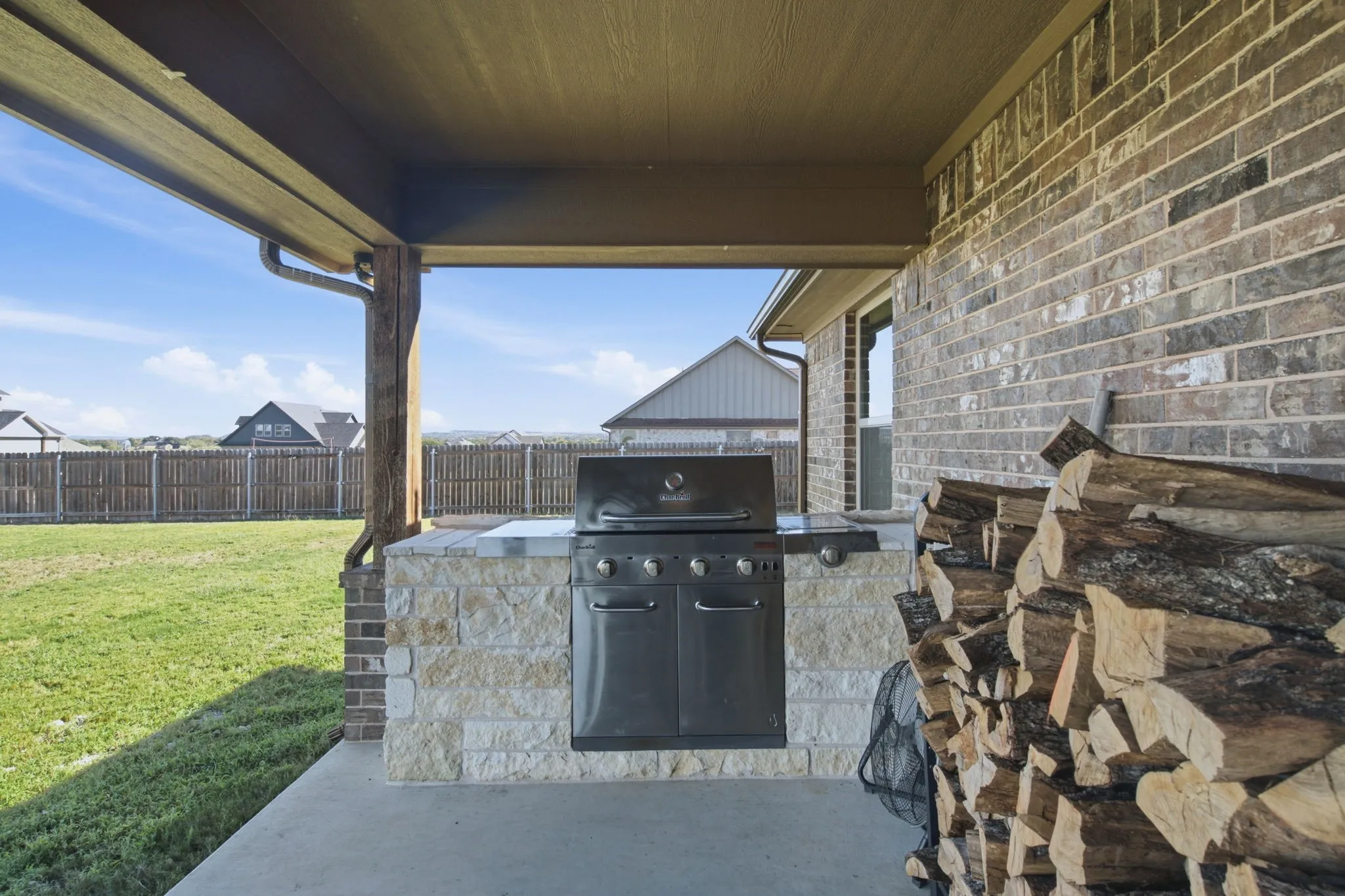 Covered patio featuring a built-in outdoor grill, a stone-clad grill station, and a brick exterior wall