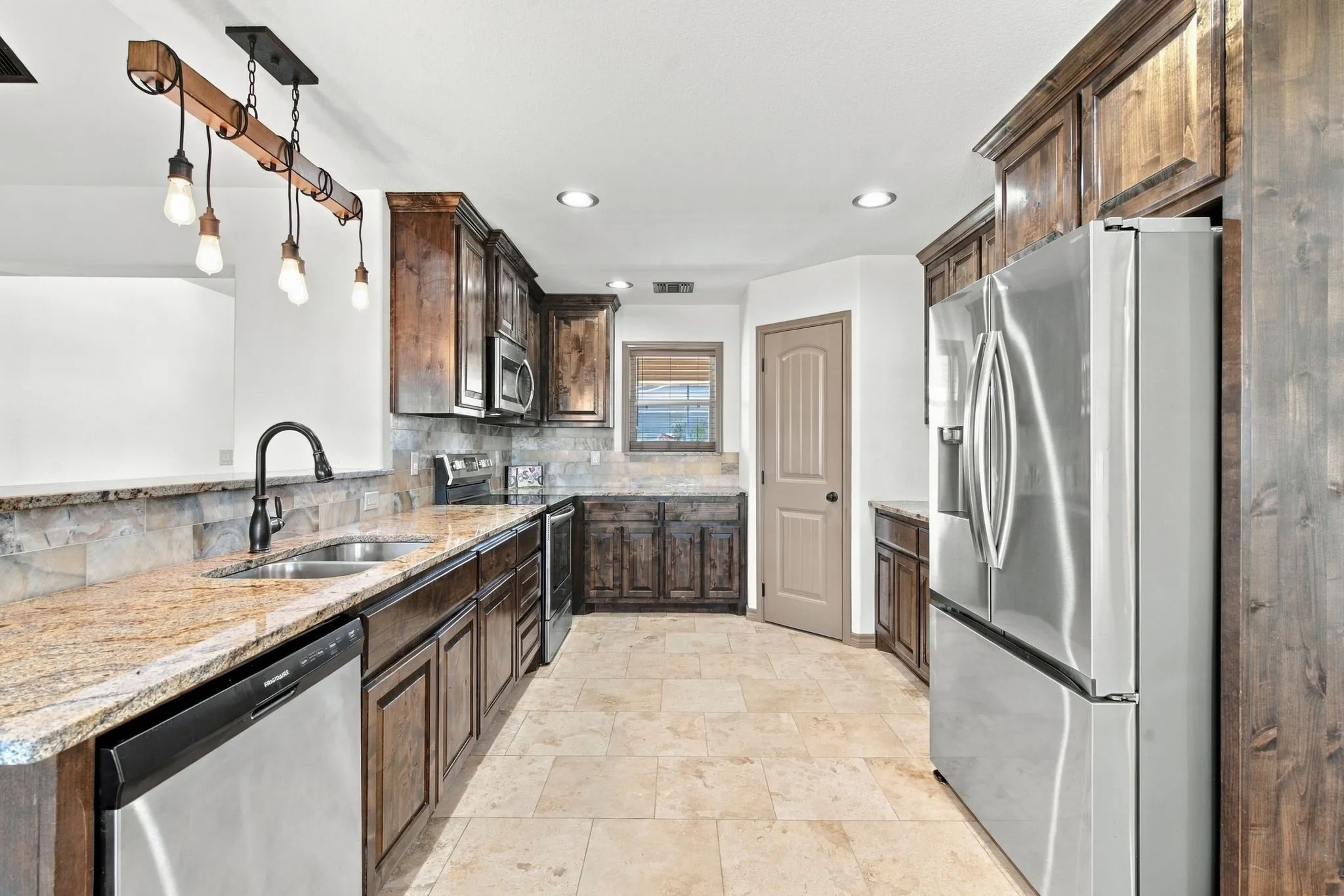 Kitchen featuring wood cabinetry, stainless steel appliances, granite countertops, tile flooring, and a stone backsplash