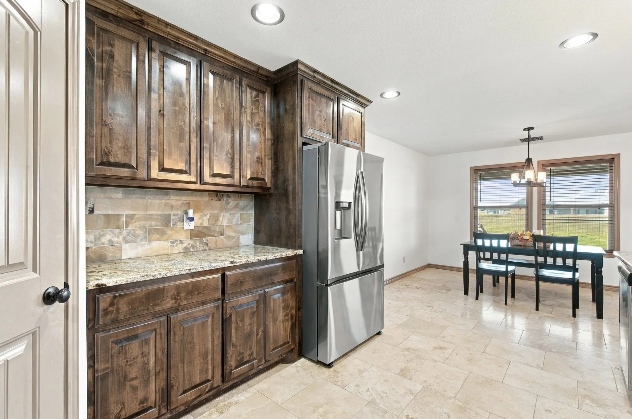 Expansive kitchen featuring wood cabinetry, granite-finish countertops, tiled backsplash, and recessed lighting