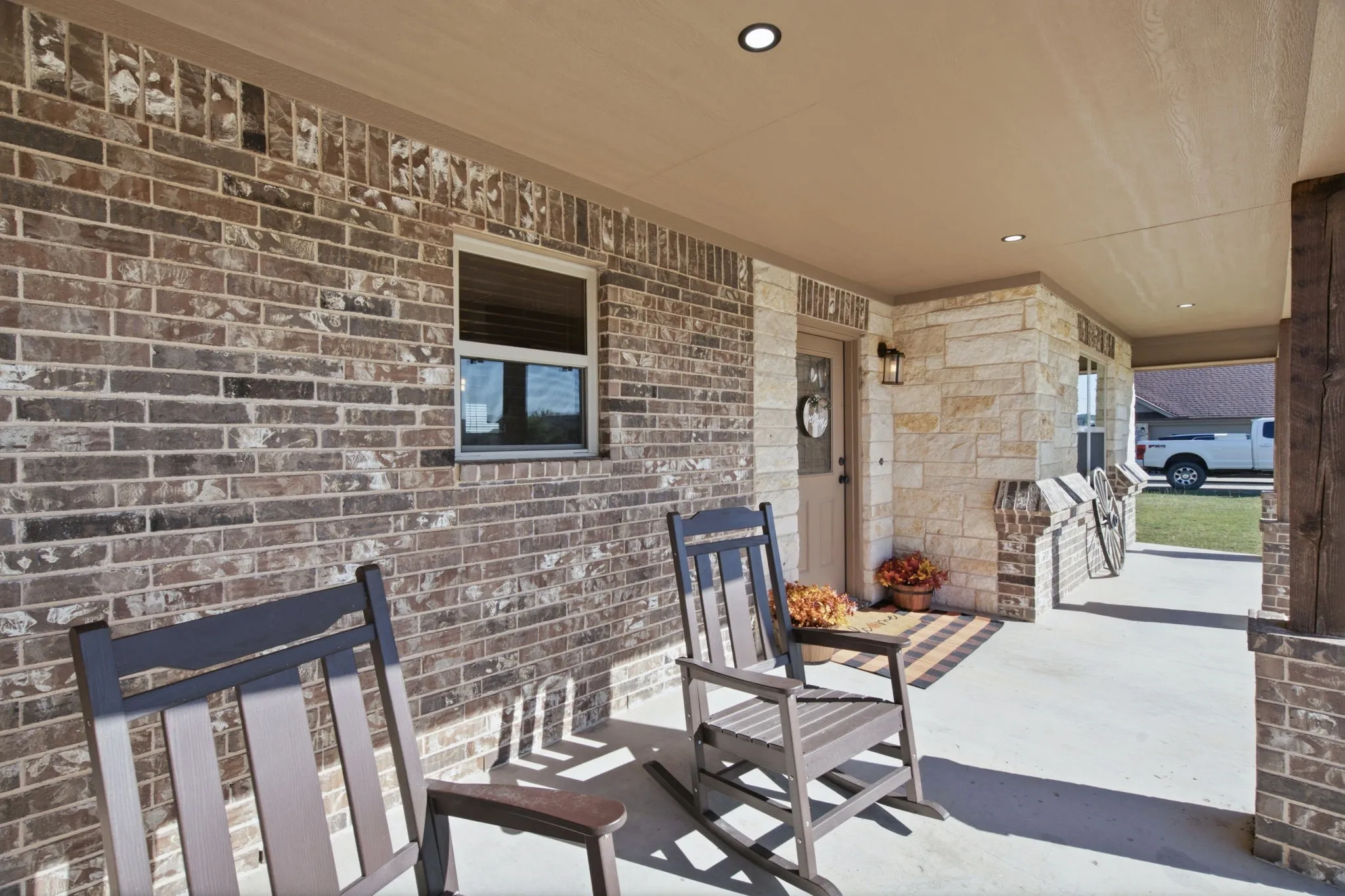Covered front porch featuring brick and stone veneer, recessed ceiling lighting, and a solid wood entry door