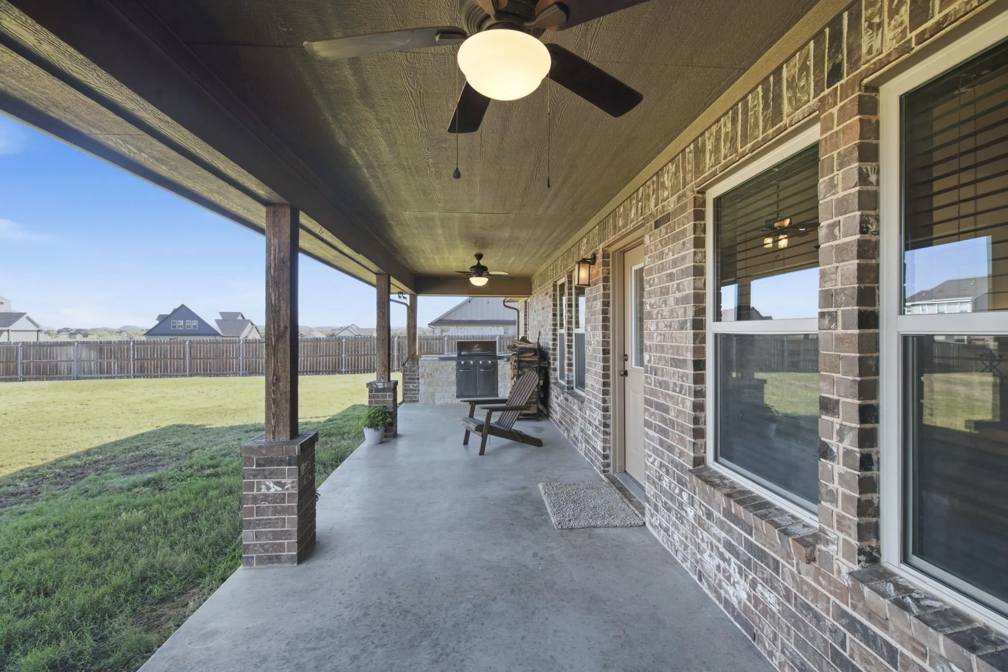 Covered patio featuring concrete flooring, ceiling fans, and brick columns