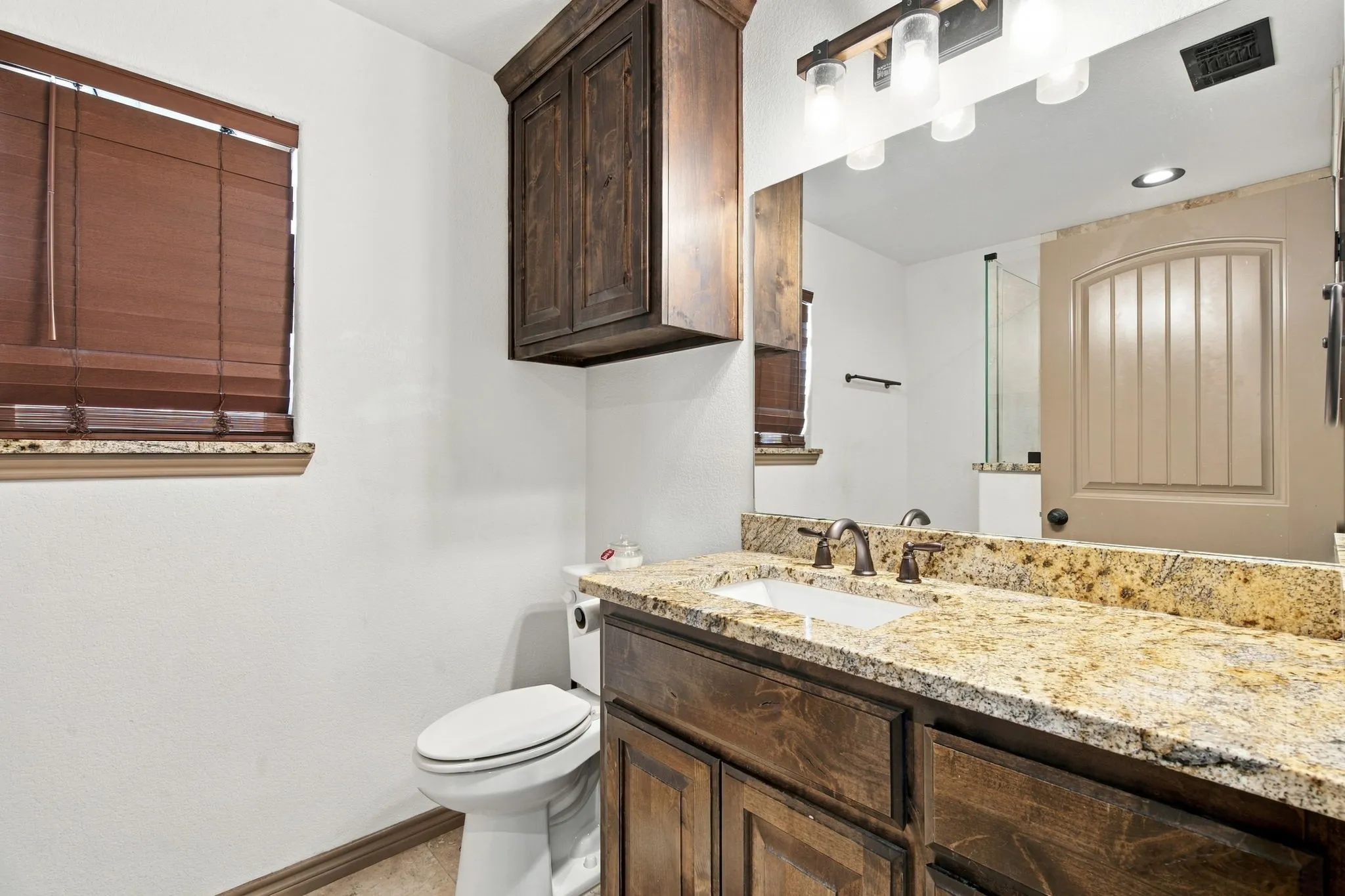 Vanity with a granite countertop, undermount sink, and bronze-finish faucet