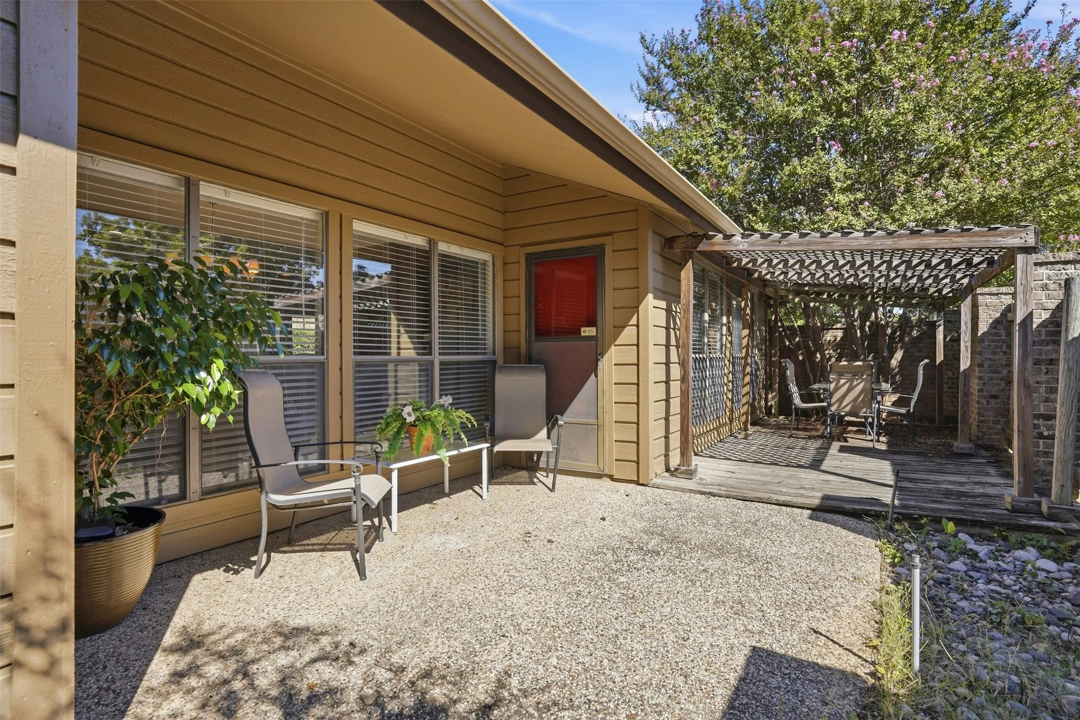 Exterior patio with a pergola-covered wooden deck, concrete paving, and siding exterior