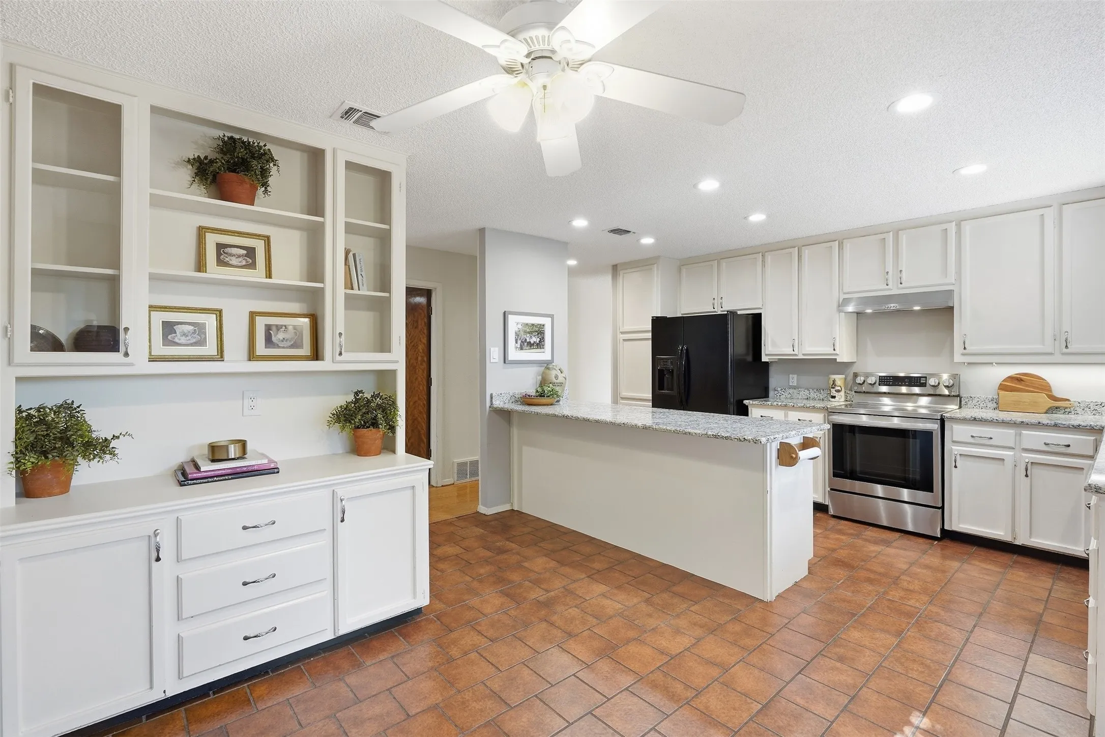 Kitchen with extensive white cabinetry, stainless steel appliances, a center island with countertop, recessed lighting, and tile flooring