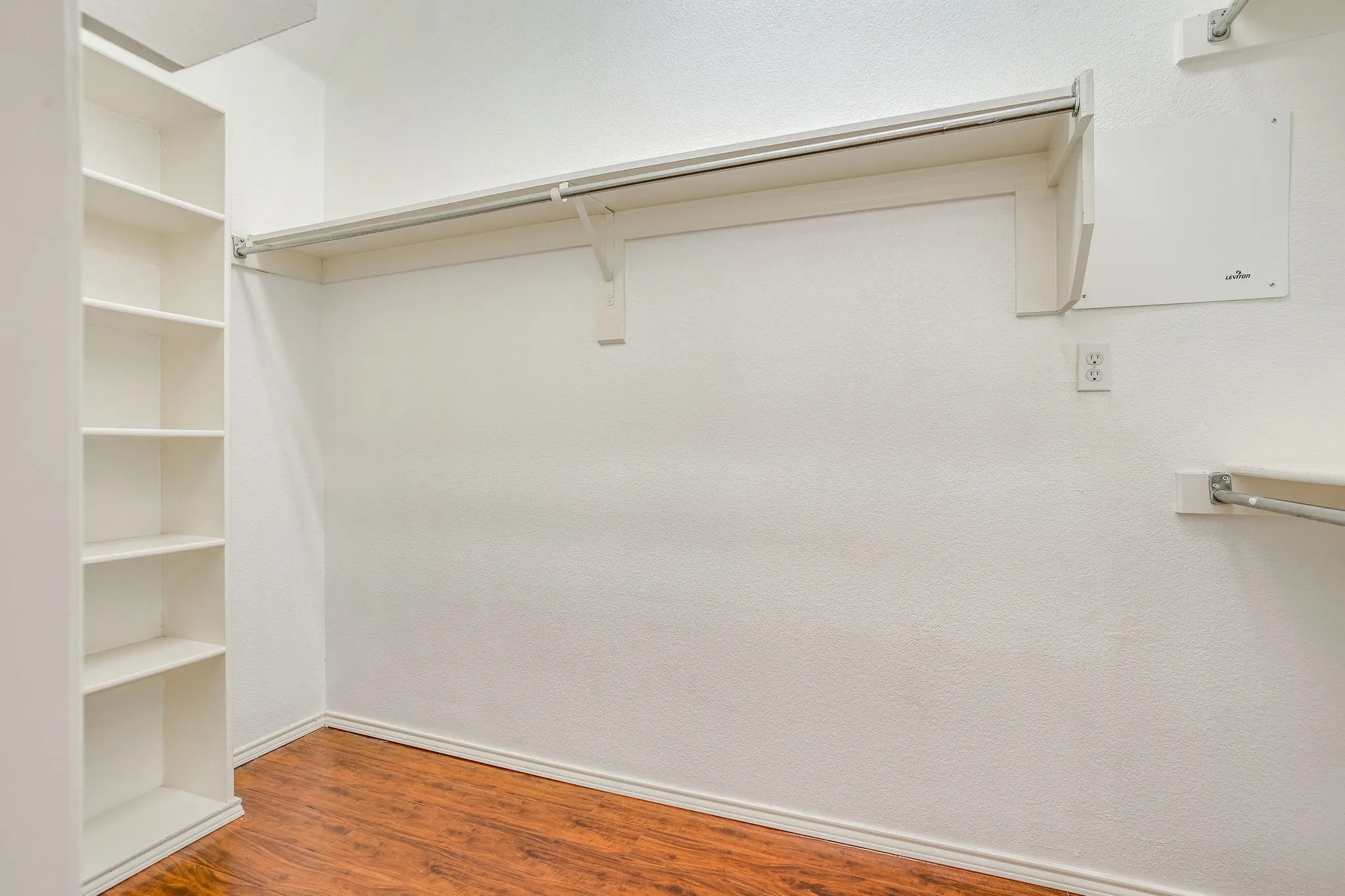 Built-in shelving, wood-finish flooring, and white walls with baseboards