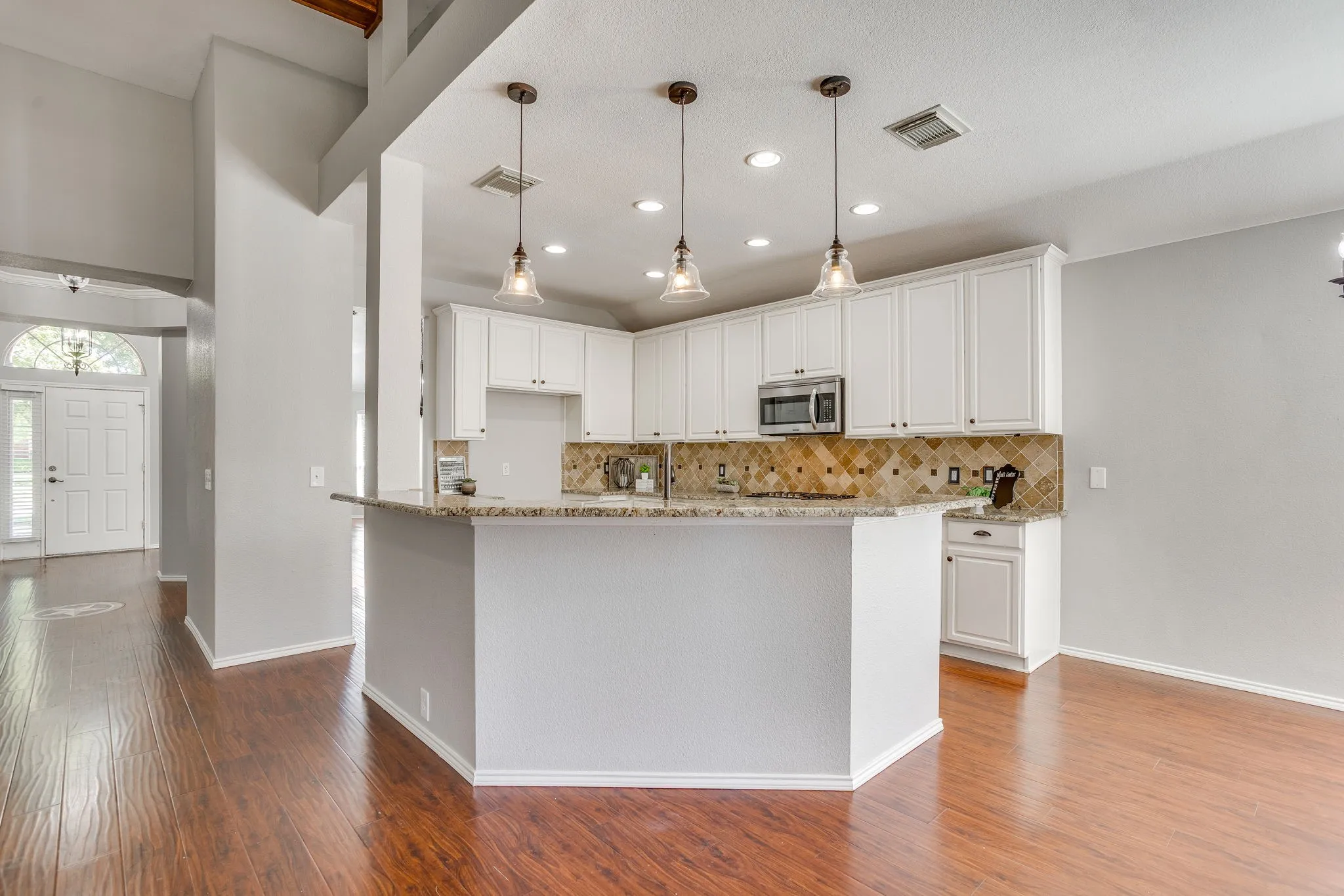 Kitchen featuring white cabinetry, a built-in microwave, pendant lighting, and wood-finish flooring