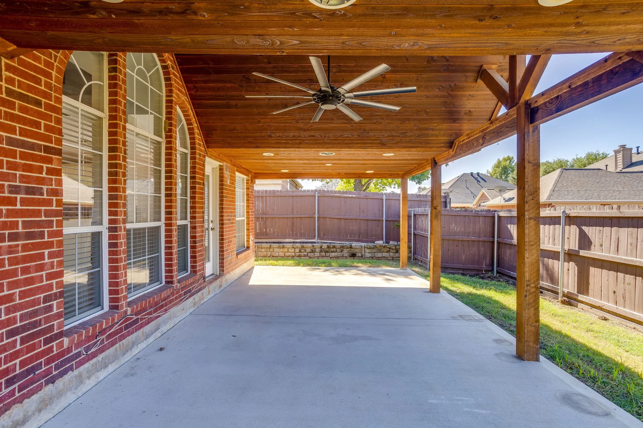 Expansive covered patio featuring a wood-plank ceiling with recessed lighting and a ceiling fan
