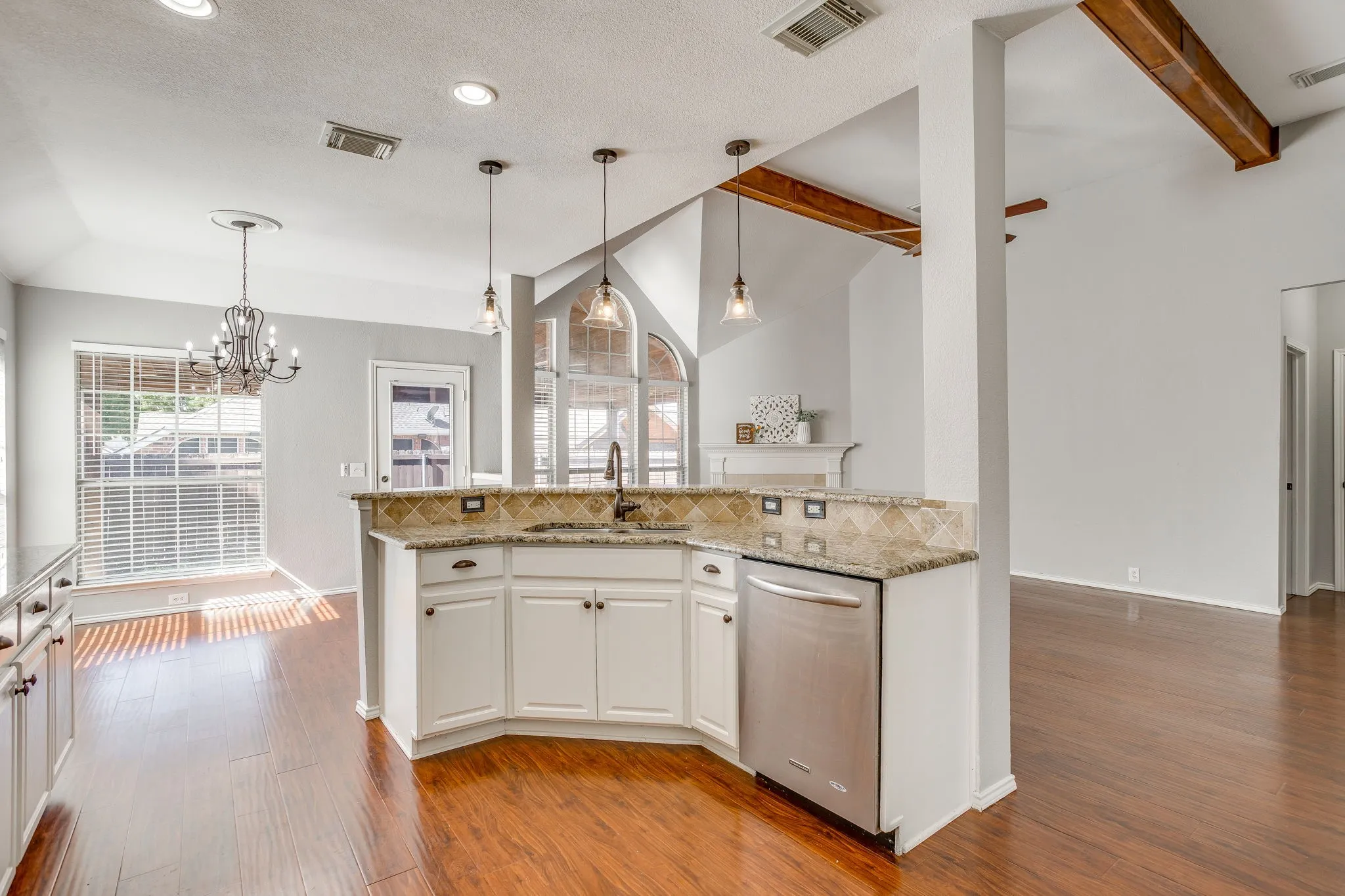 Kitchen island featuring white cabinetry, a stainless steel dishwasher, and a sink with a gooseneck faucet