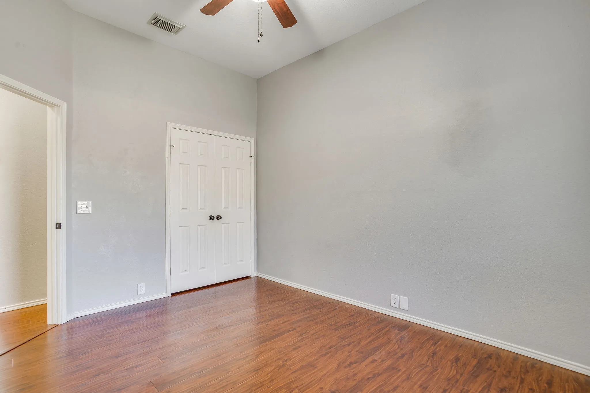 Vaulted ceiling with a ceiling fan, wood-finish flooring, and bi-fold closet doors