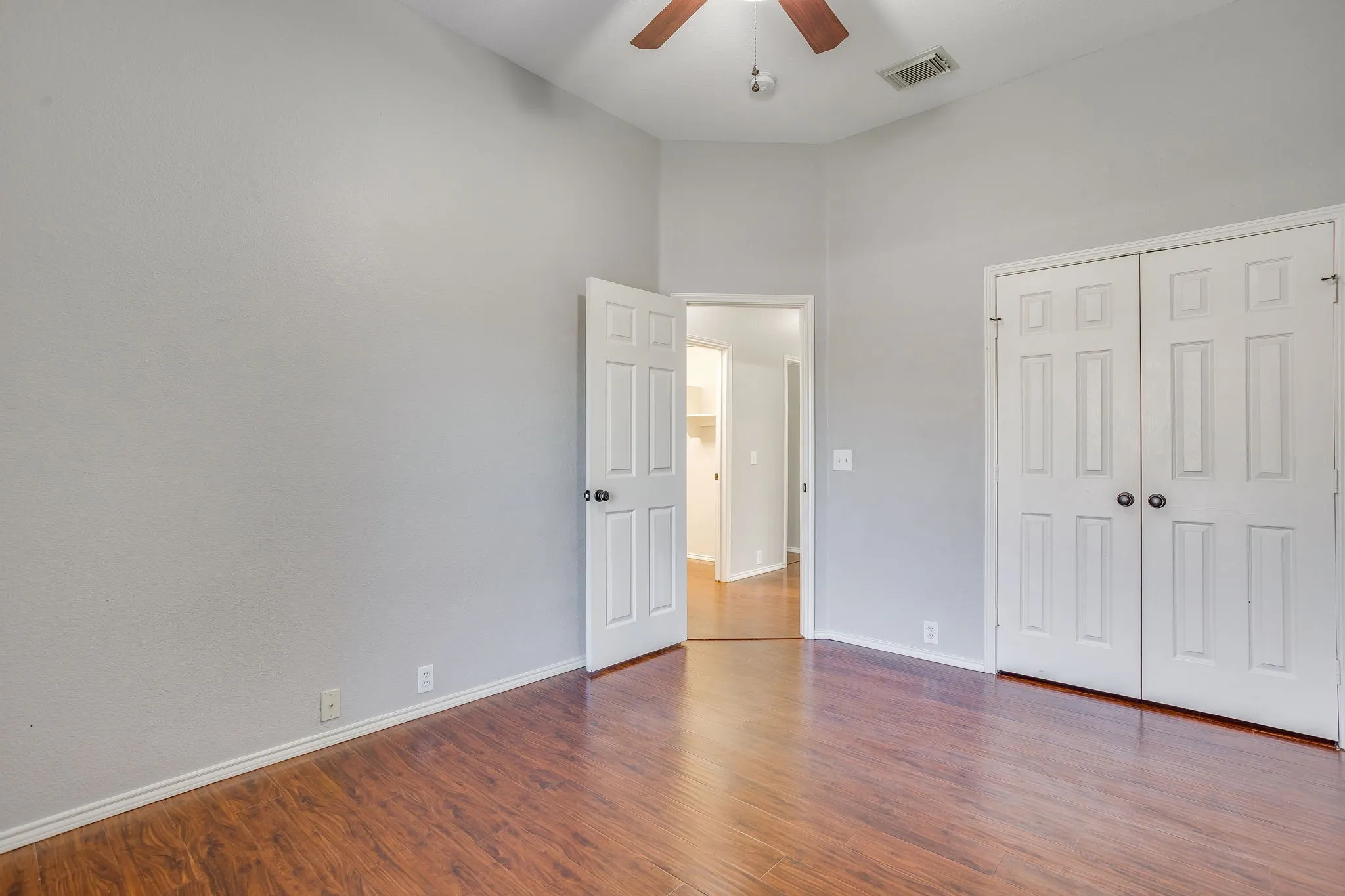 Vaulted ceiling with a ceiling fan, wood-finish flooring, and white paneled doors