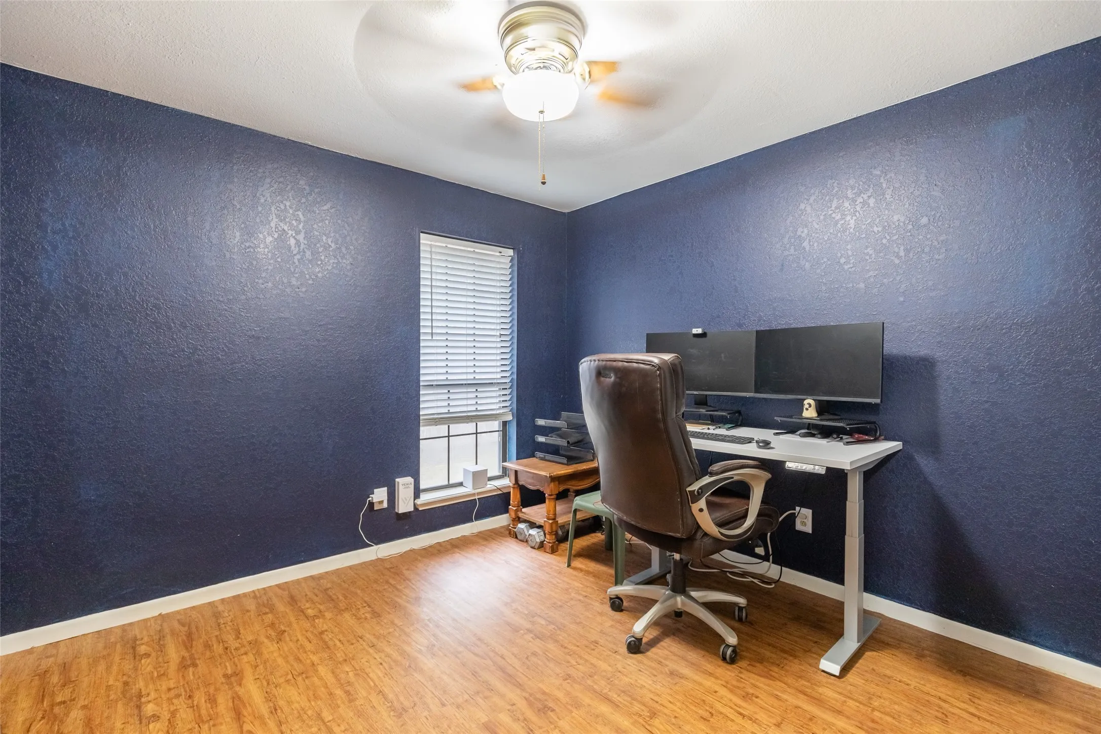 Wood-finish flooring, textured wall finish, and a ceiling fan with integrated lighting