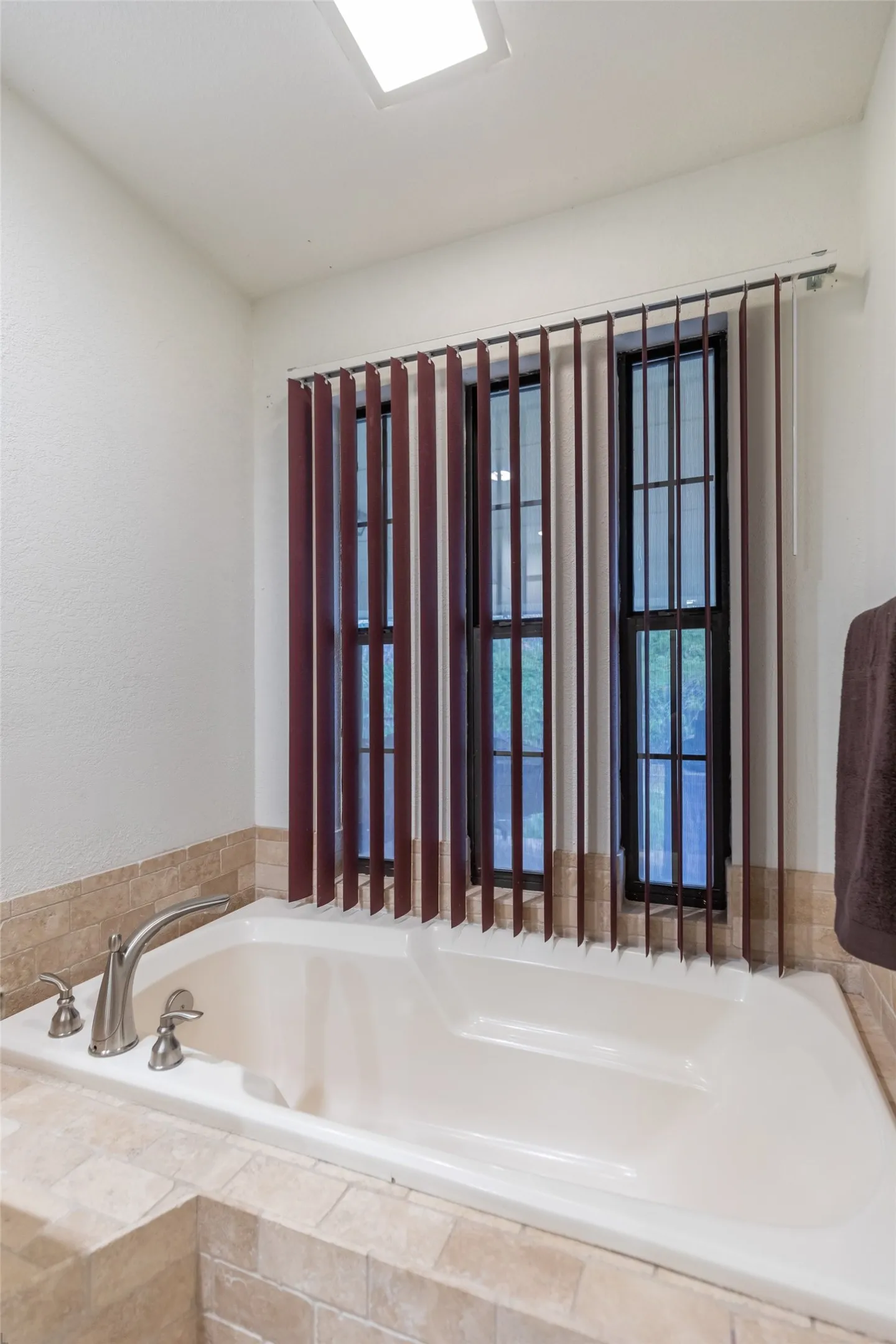 Built-in soaking tub with brushed nickel fixtures and a tiled surround