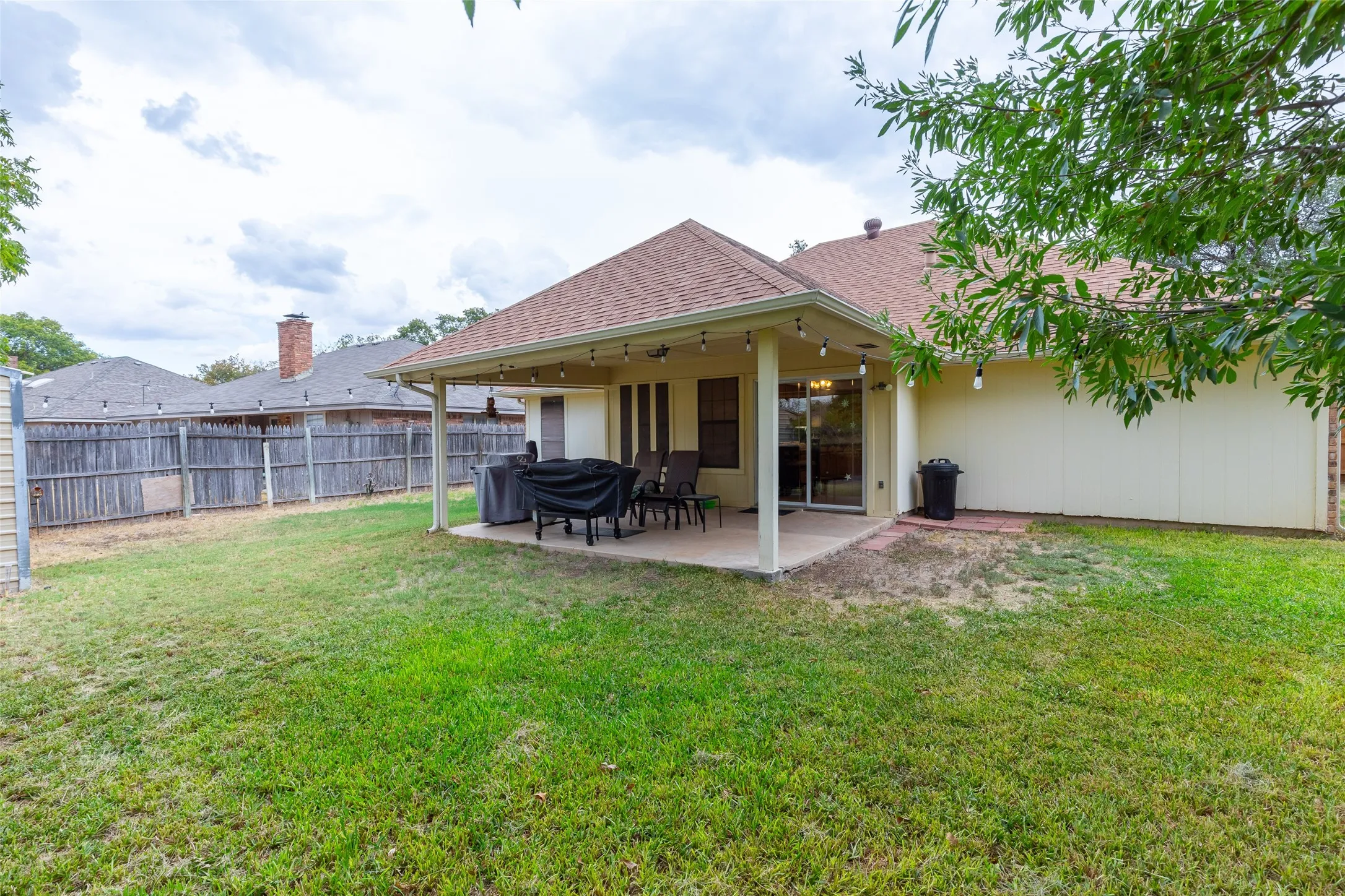 Expansive backyard featuring a covered patio, concrete slab, and wood privacy fencing