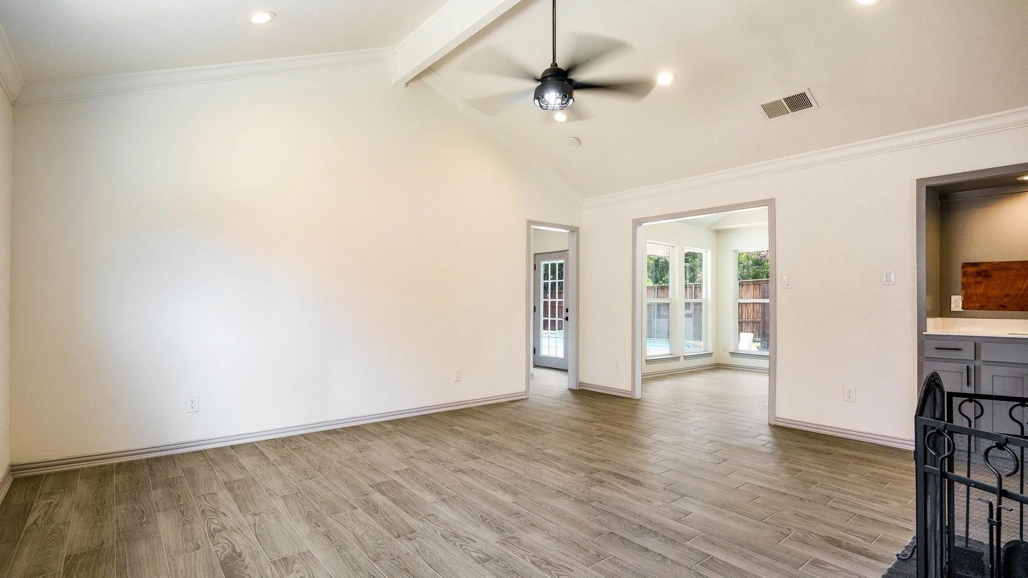 Vaulted ceiling with exposed beam, wood-finish flooring, recessed lighting, and a contemporary ceiling fan