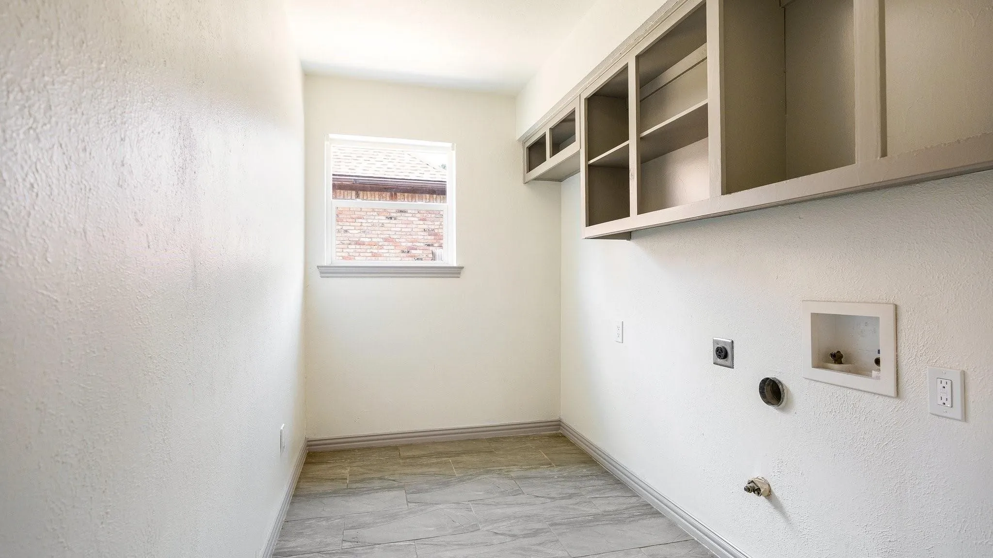 Built-in cabinetry with open shelving, window with trim, tile flooring, and light-toned walls