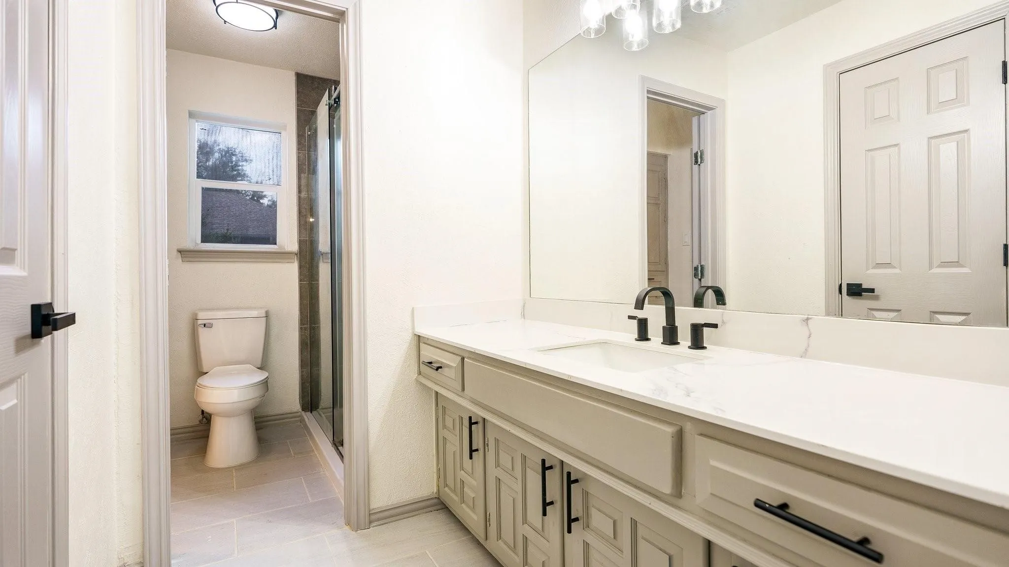 Built-in vanity with light-colored cabinetry, matte black hardware, and a single basin sink