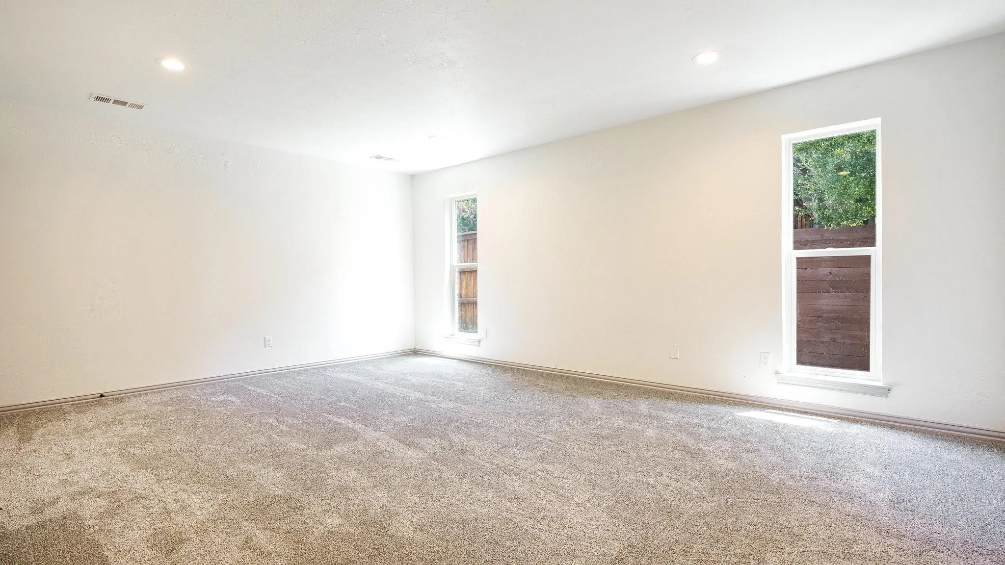 Spacious room with light-colored carpeting and white walls