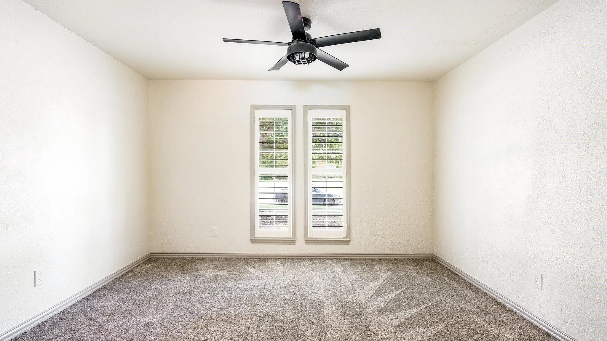 Textured walls, ceiling fan, and carpeted flooring