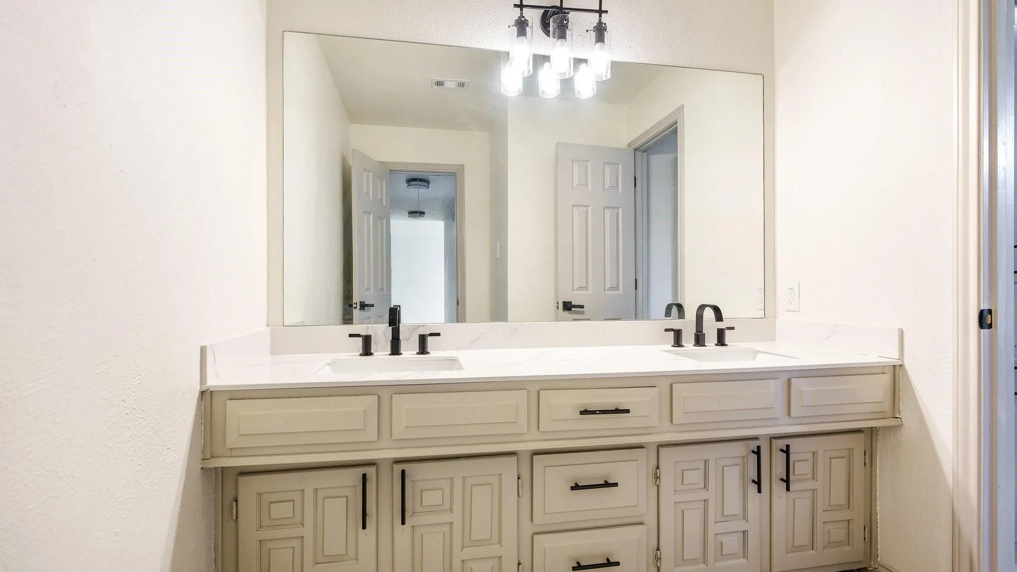 Dual vanity with white countertop, undermount sinks, matte black faucets, and coordinating cabinet hardware