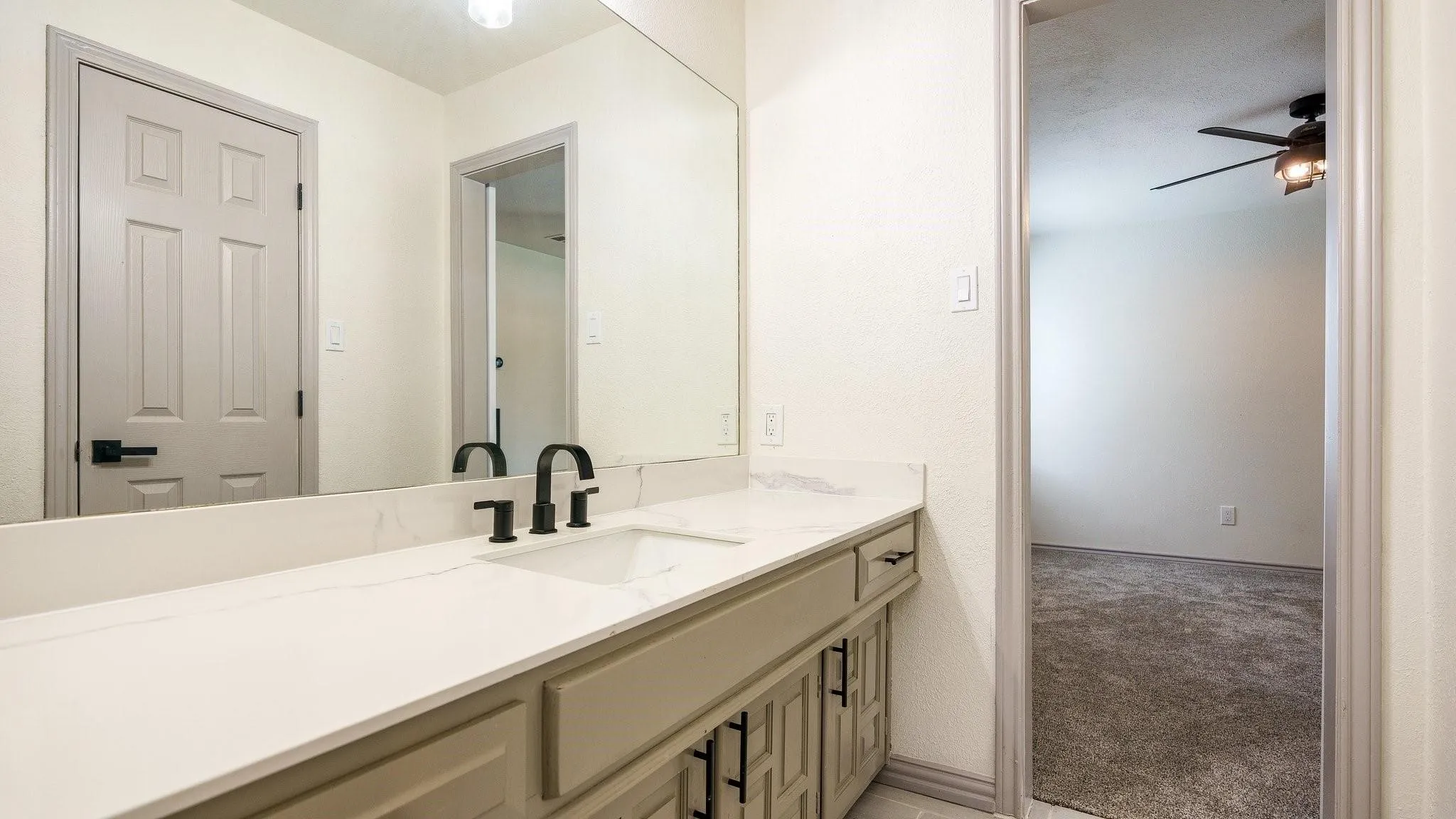 Vanity with a single basin sink, matte black faucet, and white countertop
