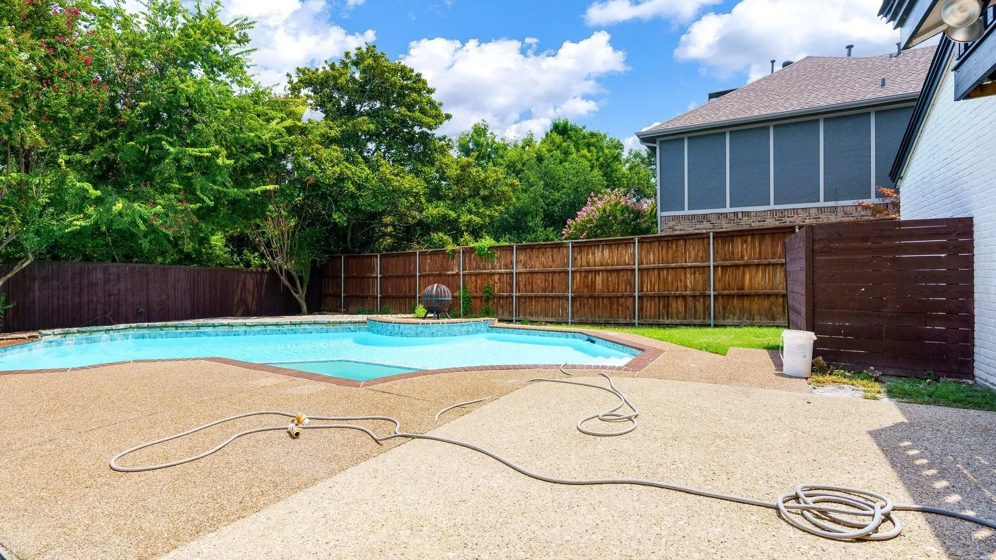 Outdoor swimming pool with integrated spa and surrounding concrete decking