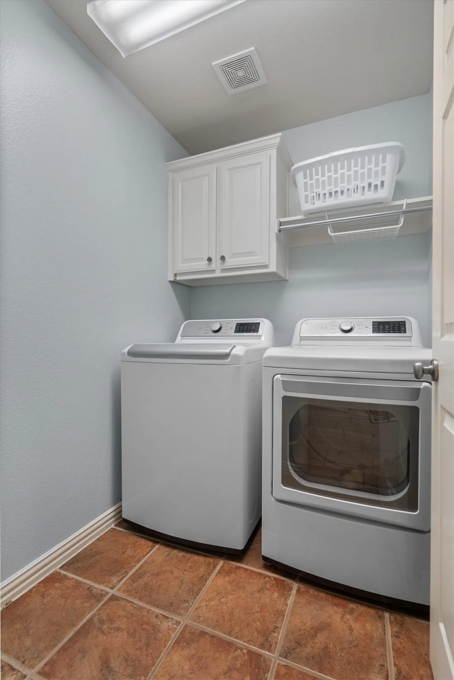 Laundry area featuring tiled flooring, white upper cabinetry, and a white wire shelf