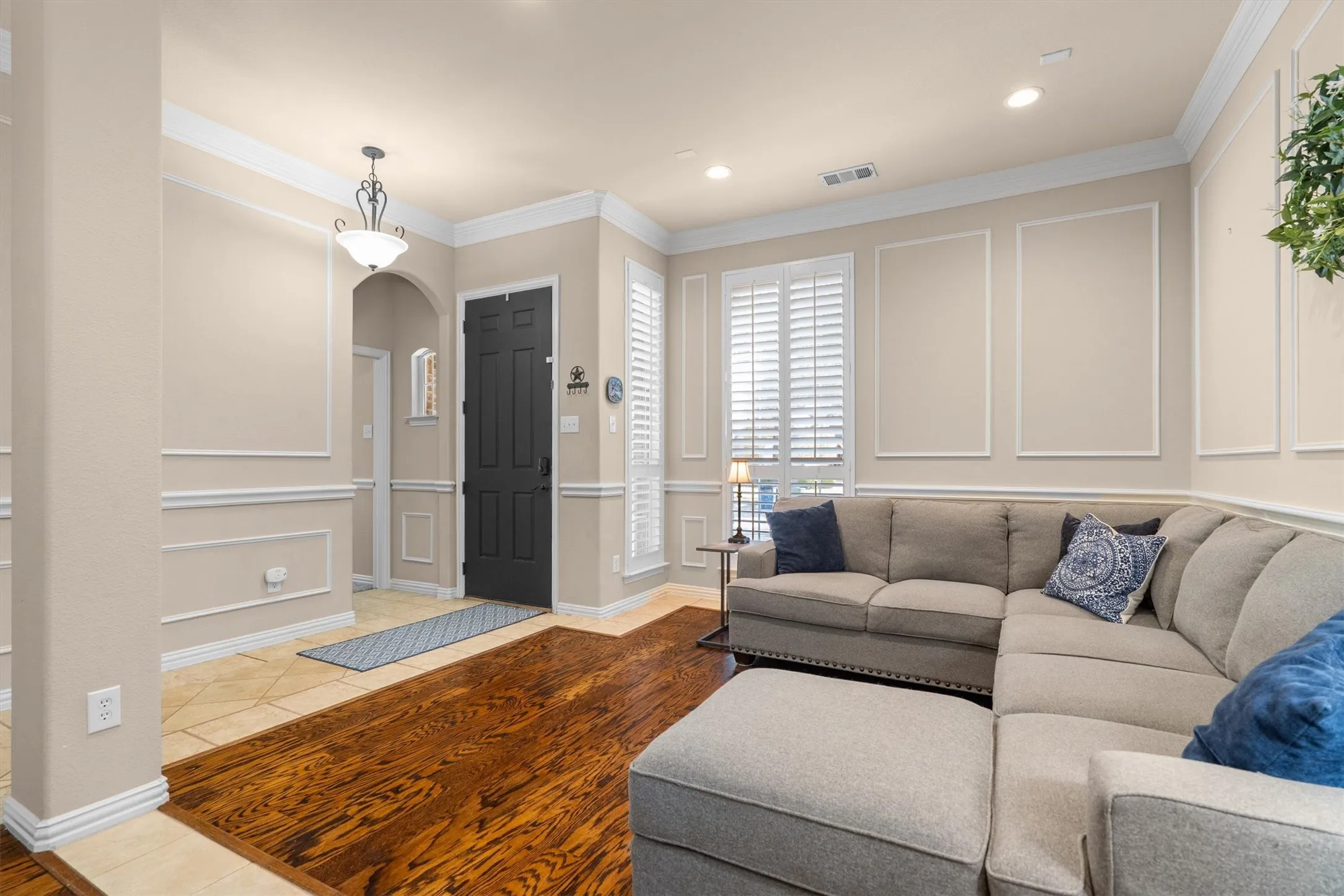 Wood-finish flooring, recessed lighting, crown molding, plantation shutters, and decorative wall paneling