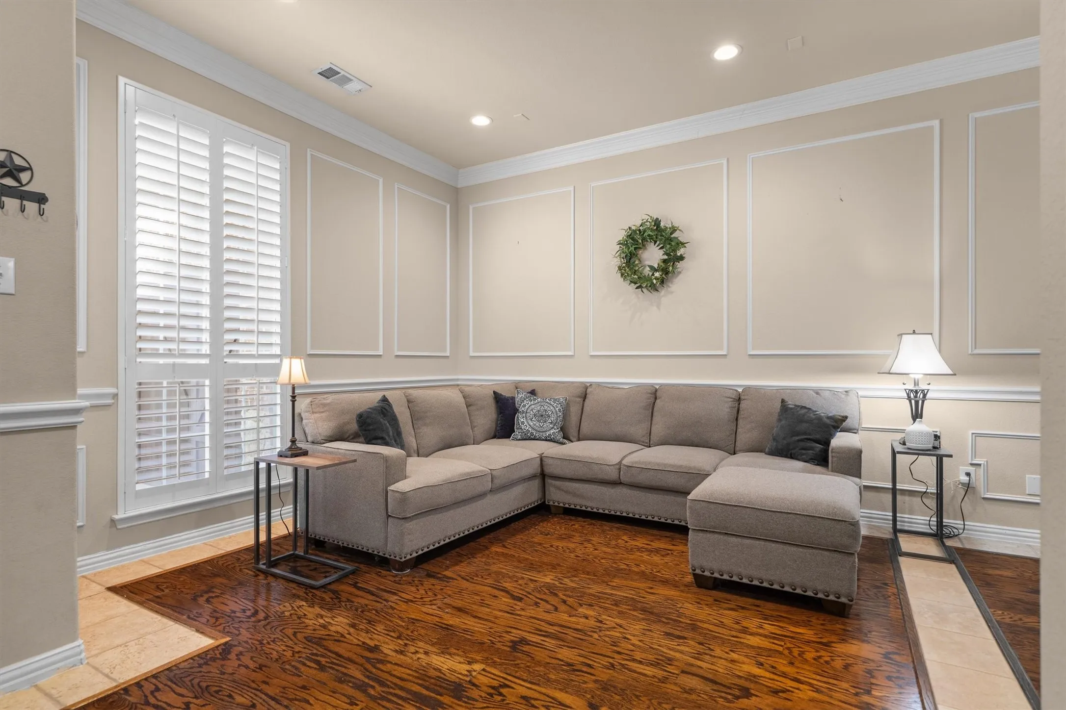 Wood-finish flooring, white plantation shutters, decorative wall molding, and recessed ceiling lighting
