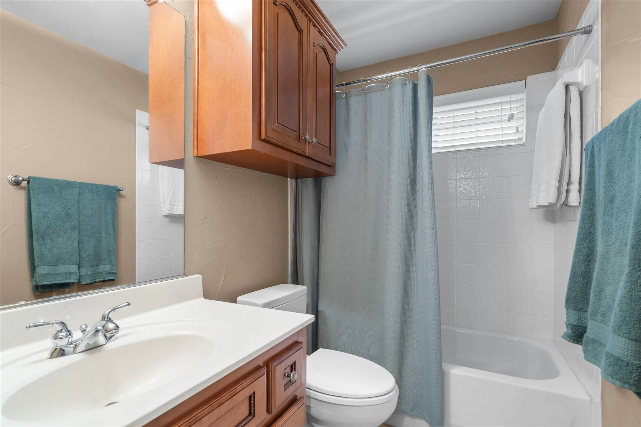 Bathroom featuring a vanity with an integrated sink, polished chrome faucet, wood-finish cabinetry, and a built-in bathtub with tiled surround