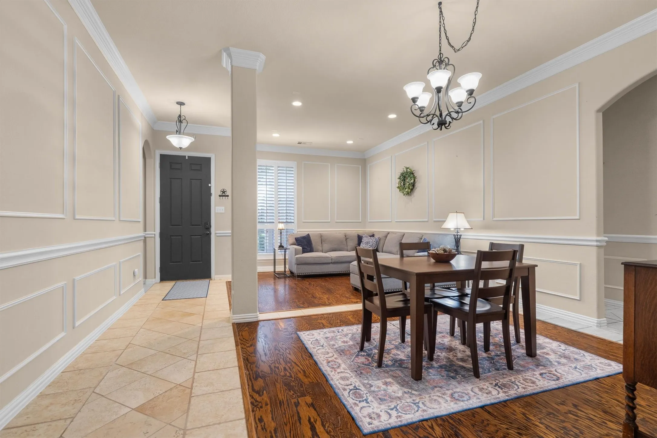 Tile flooring entry, wood-finish flooring, decorative wall molding, archway, chandelier