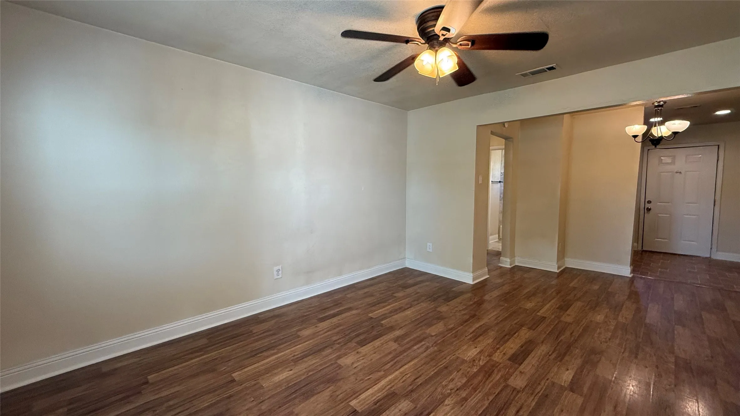 Spacious interior with wood-finish flooring, ceiling fan with integrated lighting, and neutral wall tones