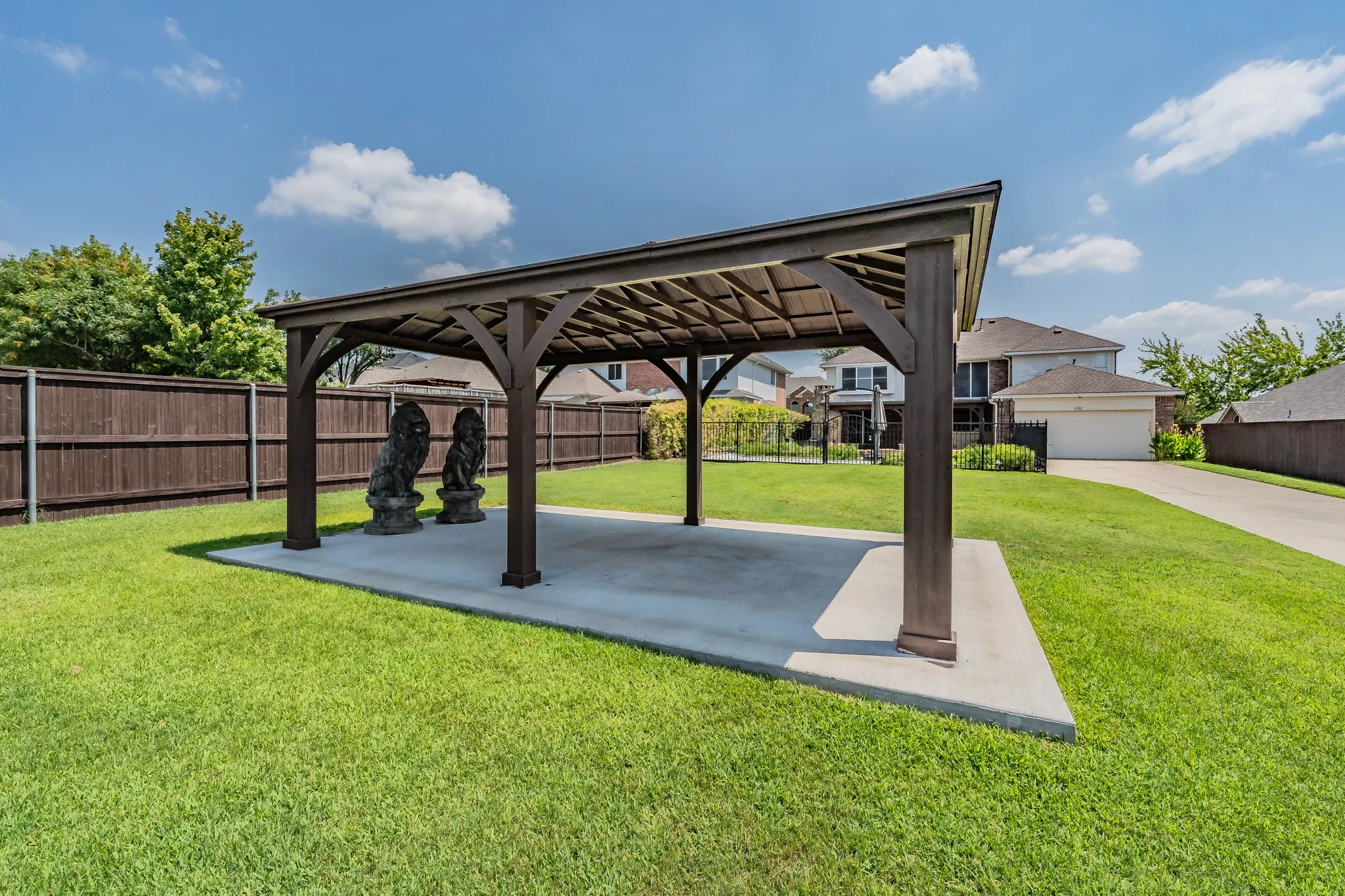 Large backyard featuring a gazebo with a concrete pad, a wooden fence, and an extended concrete driveway