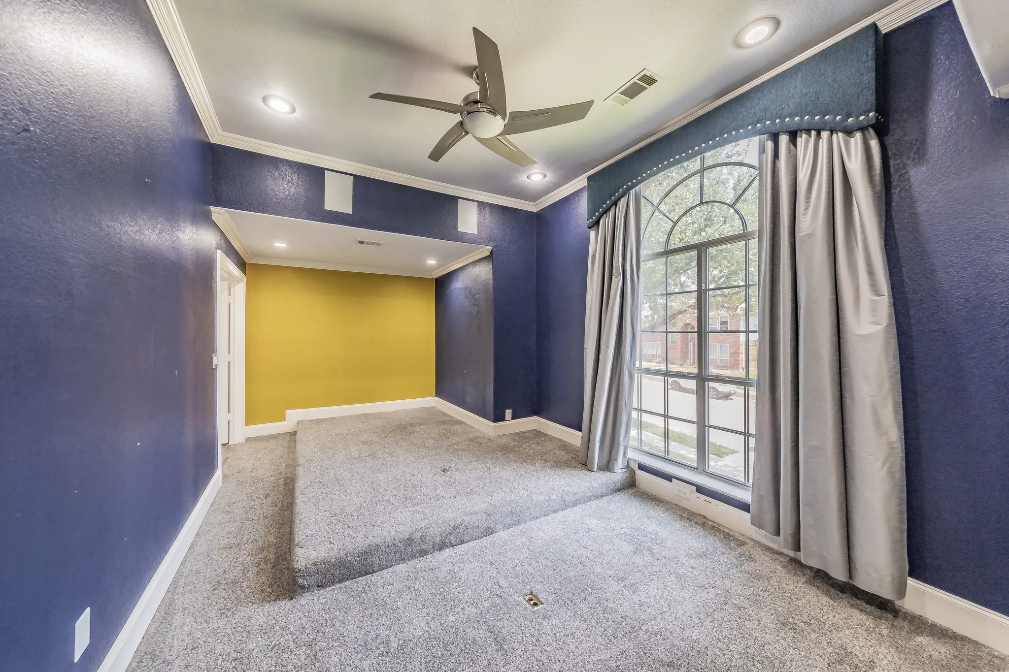 Arched window, recessed lighting, ceiling fan, carpeted flooring, built-in platform