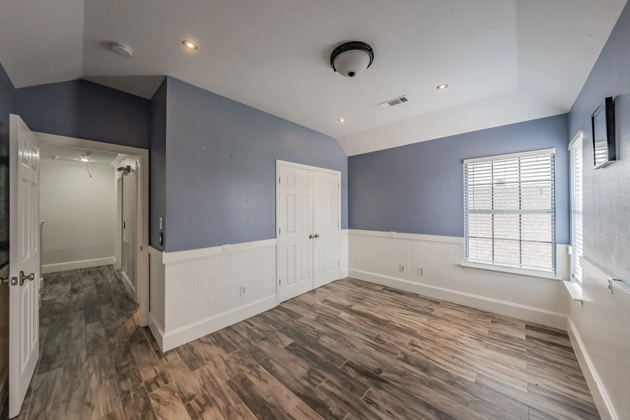 Wood-finish flooring, white beadboard wainscoting, recessed lighting, and a double-door closet
