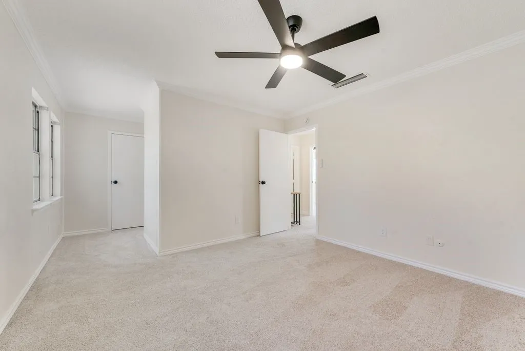 Recessed window, crown molding, light-toned carpeting, white interior doors, and a ceiling fan with integrated lighting