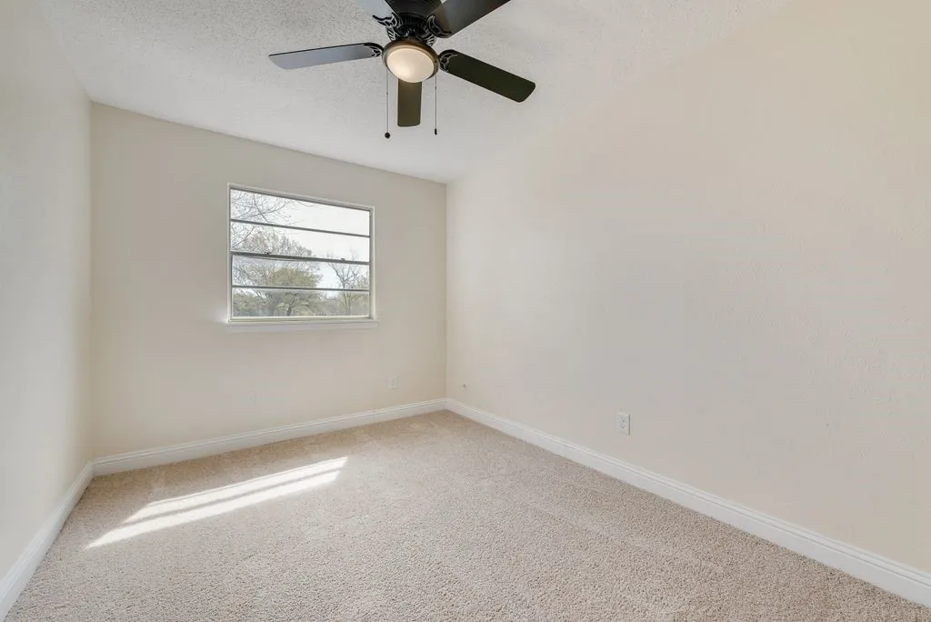Carpeted flooring, single window, white baseboards, and a ceiling fan with integrated lighting
