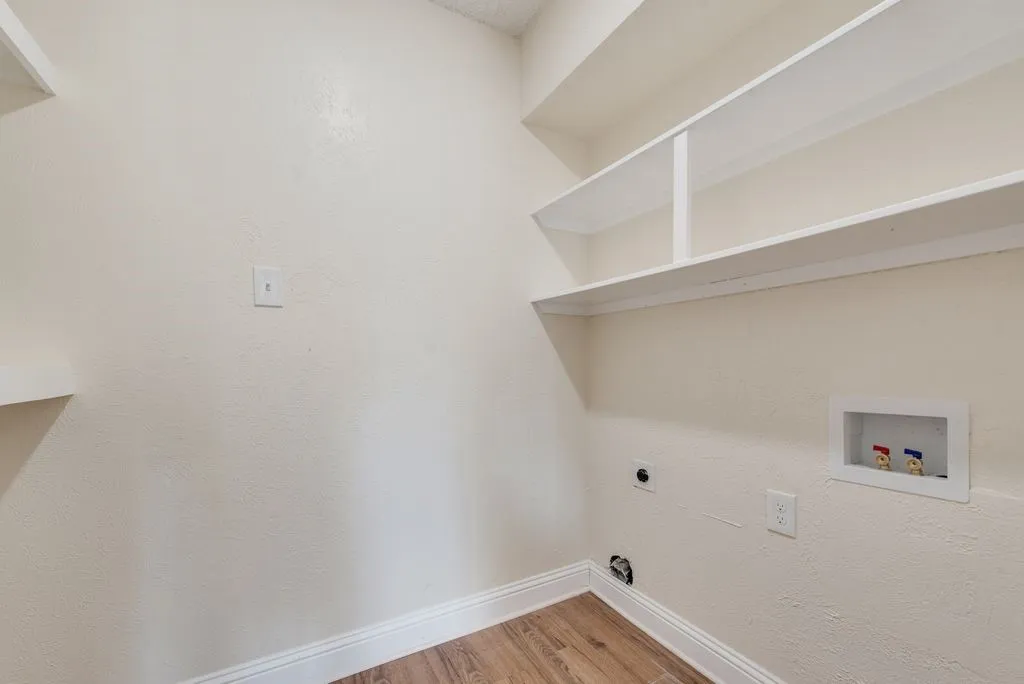 Utility space with wood-finish flooring, white baseboards, and built-in white shelving